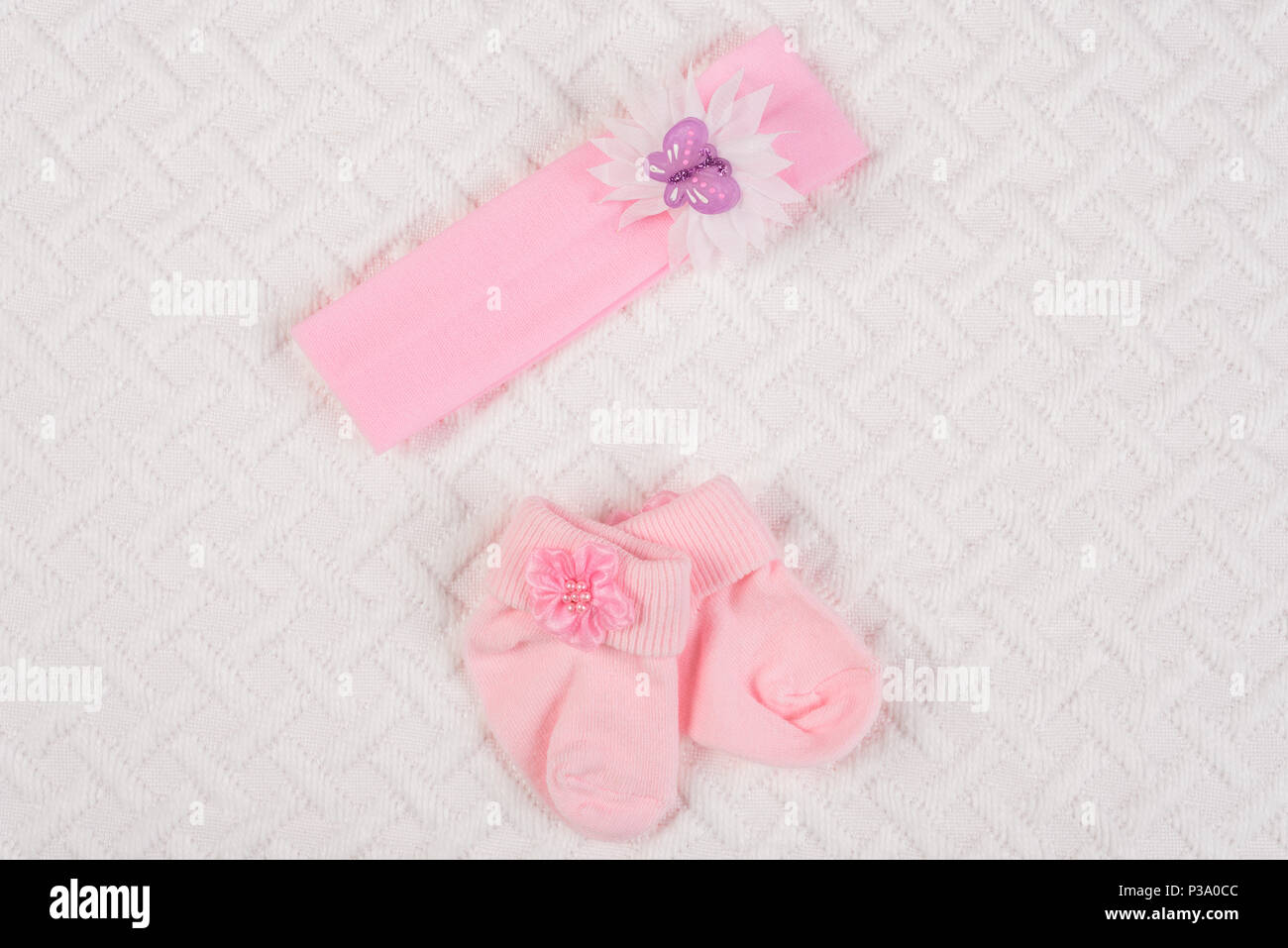 Vista superiore del neonato calze e fascia per capelli per neonato su coltre bianca. Copia spazio per il testo. Foto Stock