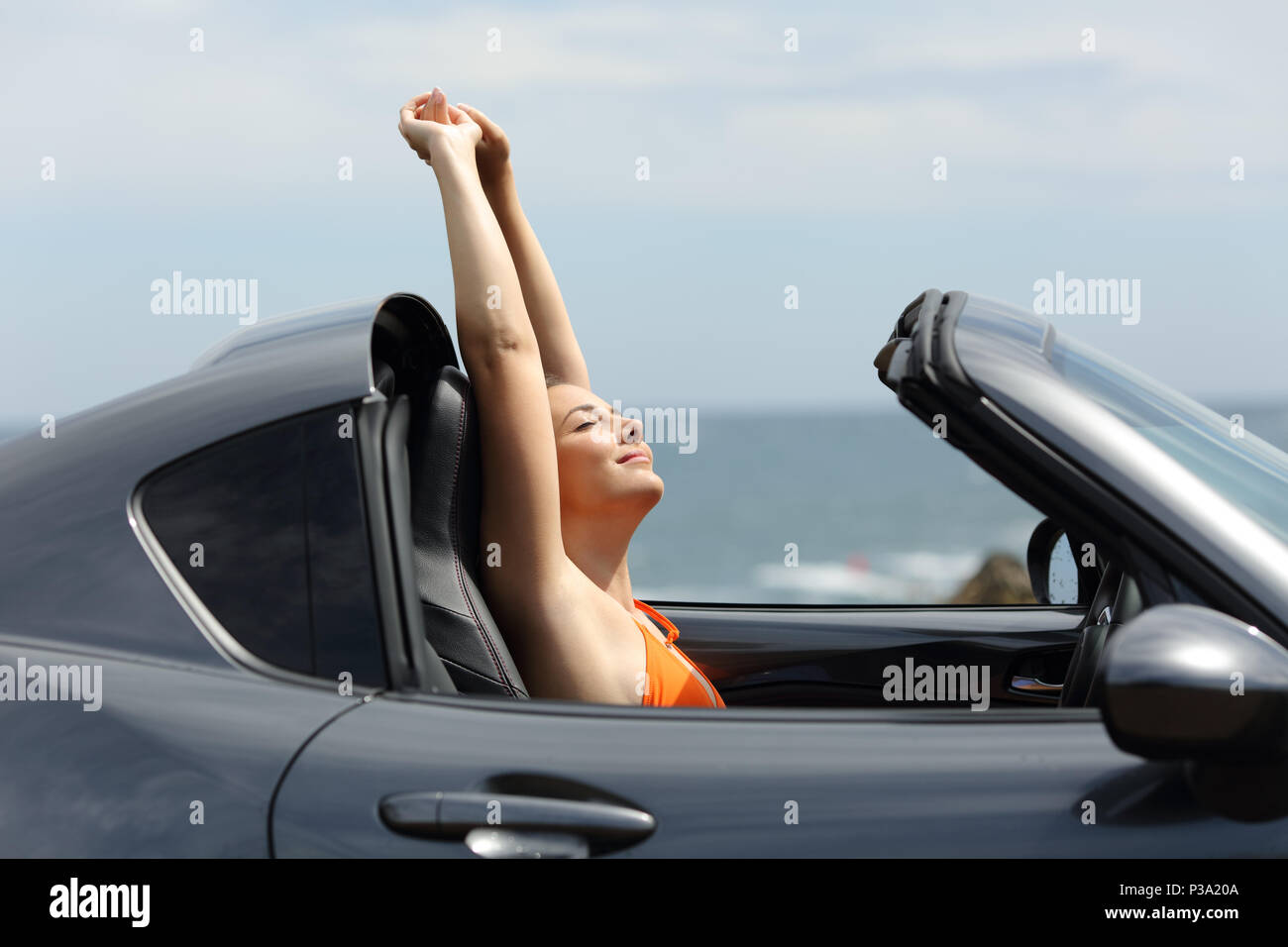 Vista laterale verticale di un turista felice godendo un roadtrip all interno di un auto durante le vacanze estive Foto Stock