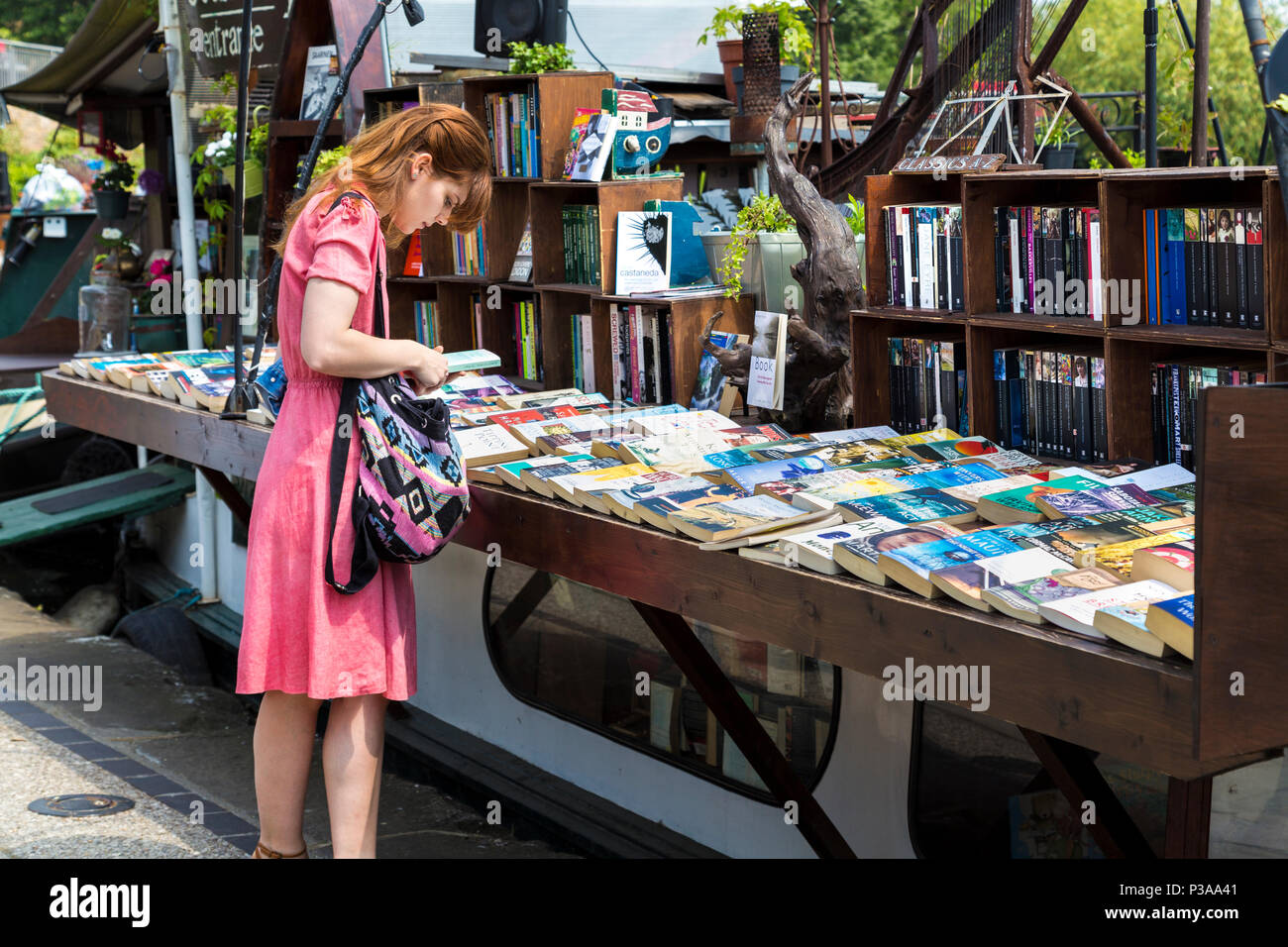 Ragazza guardando libri a parola sull'acqua floating bookshop su una chiatta, Regent's Canal vicino a Kings Cross, London, Regno Unito Foto Stock