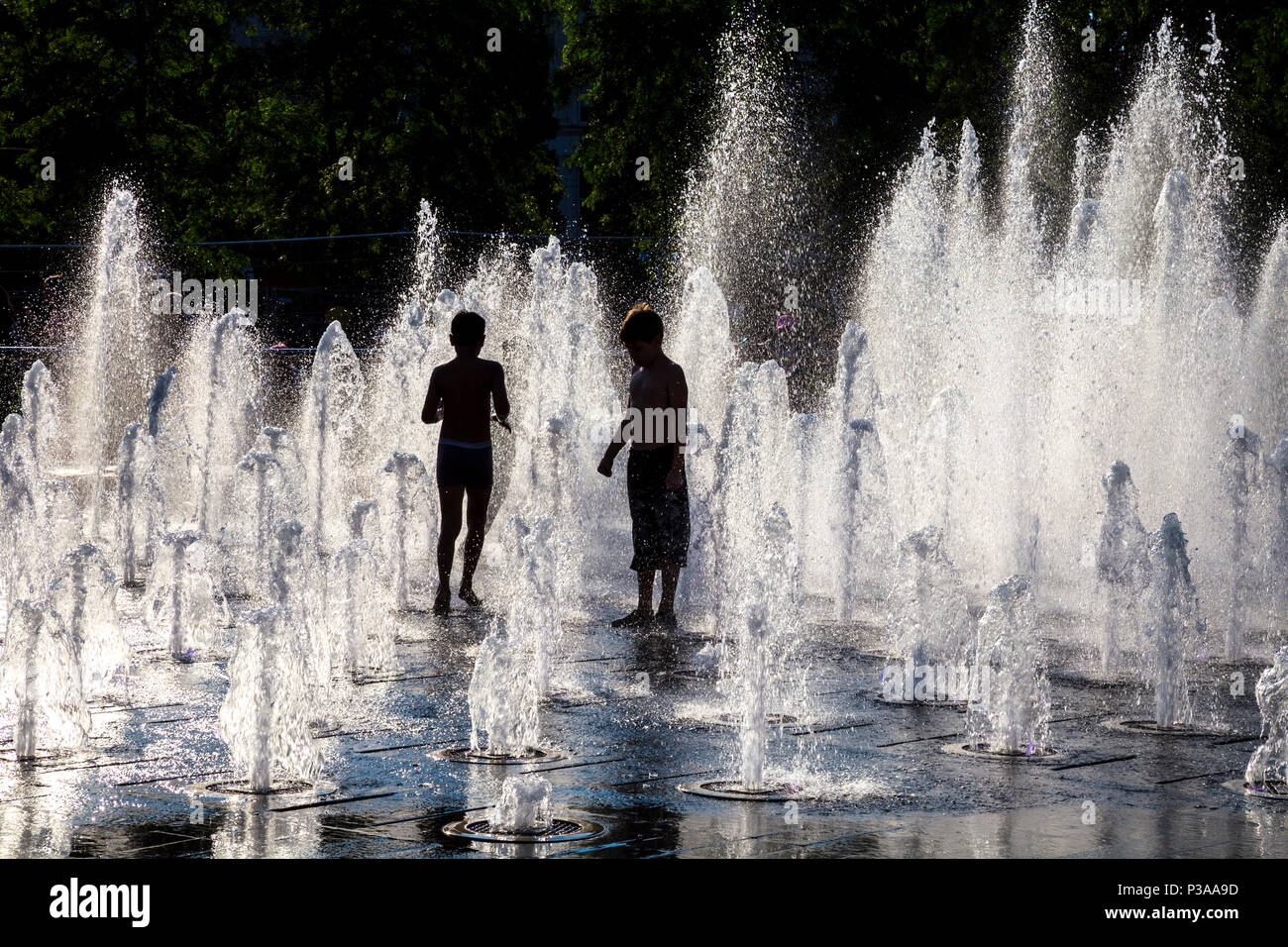Sagome di bambini che corrono attraverso una fontana in estate, Piccadilly Gardens, Manchester, Regno Unito Foto Stock