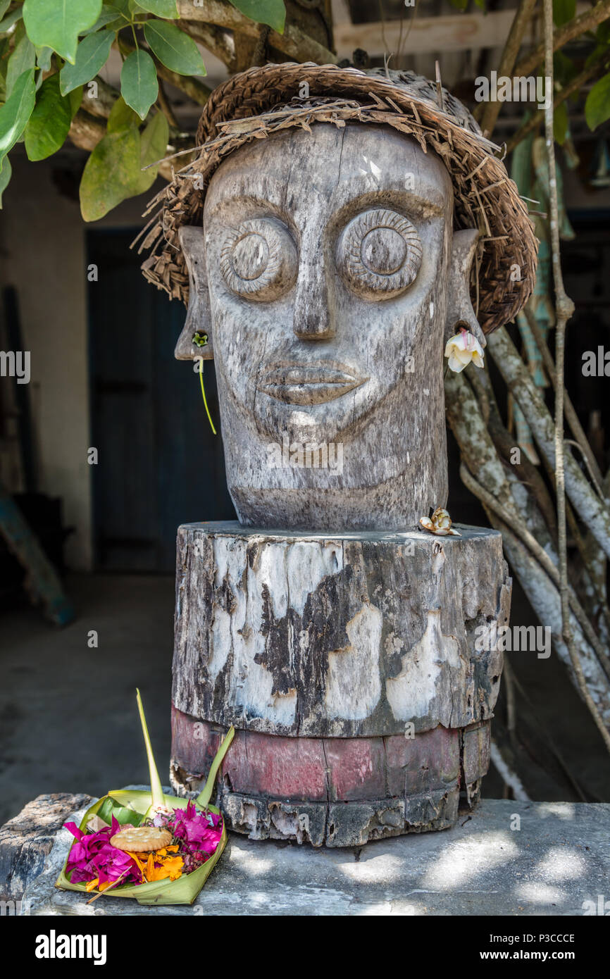 Scolpito statua in legno in stile Balinese tradizionale cappello di paglia vicino ad una casa locale Nusa Lembongan, Indonesia Foto Stock