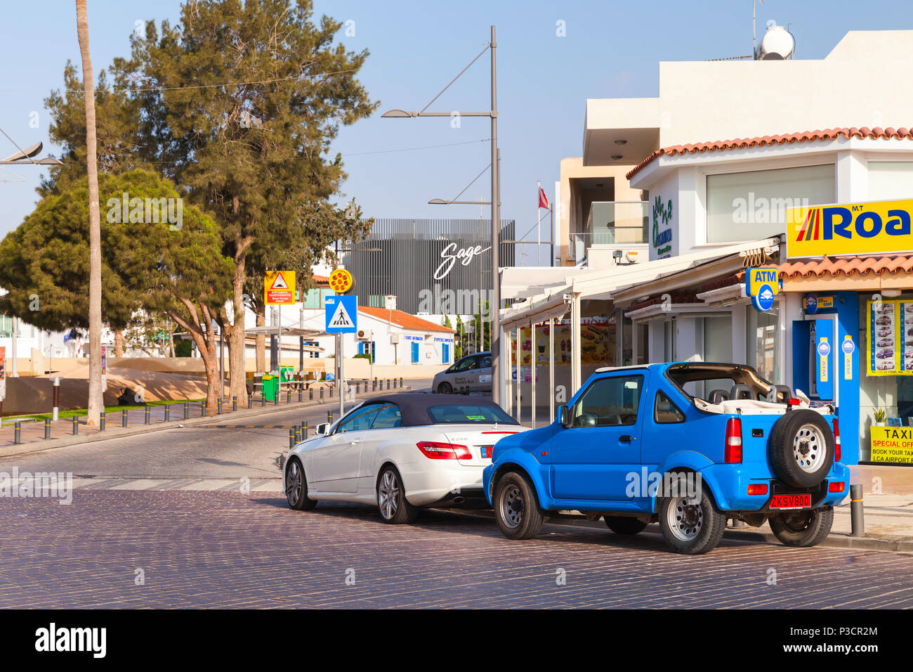 Ayia Napa, Cipro - 11 Giugno 2018: Street View di automobili parcheggiate. Agia Napa Town sulla costa sud dell'isola di Cipro in serata estiva Foto Stock