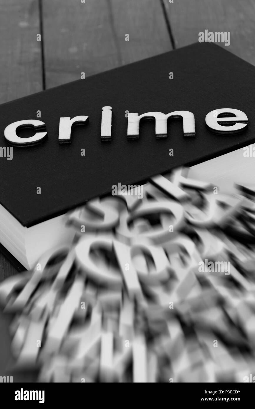 Prenota romanzo con la parola la criminalità e sfocata lettere in uscita delle pagine su uno sfondo di legno Foto Stock