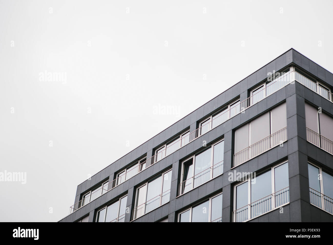 L'angolo dell'edificio con molte finestre contro il cielo grigio Foto Stock