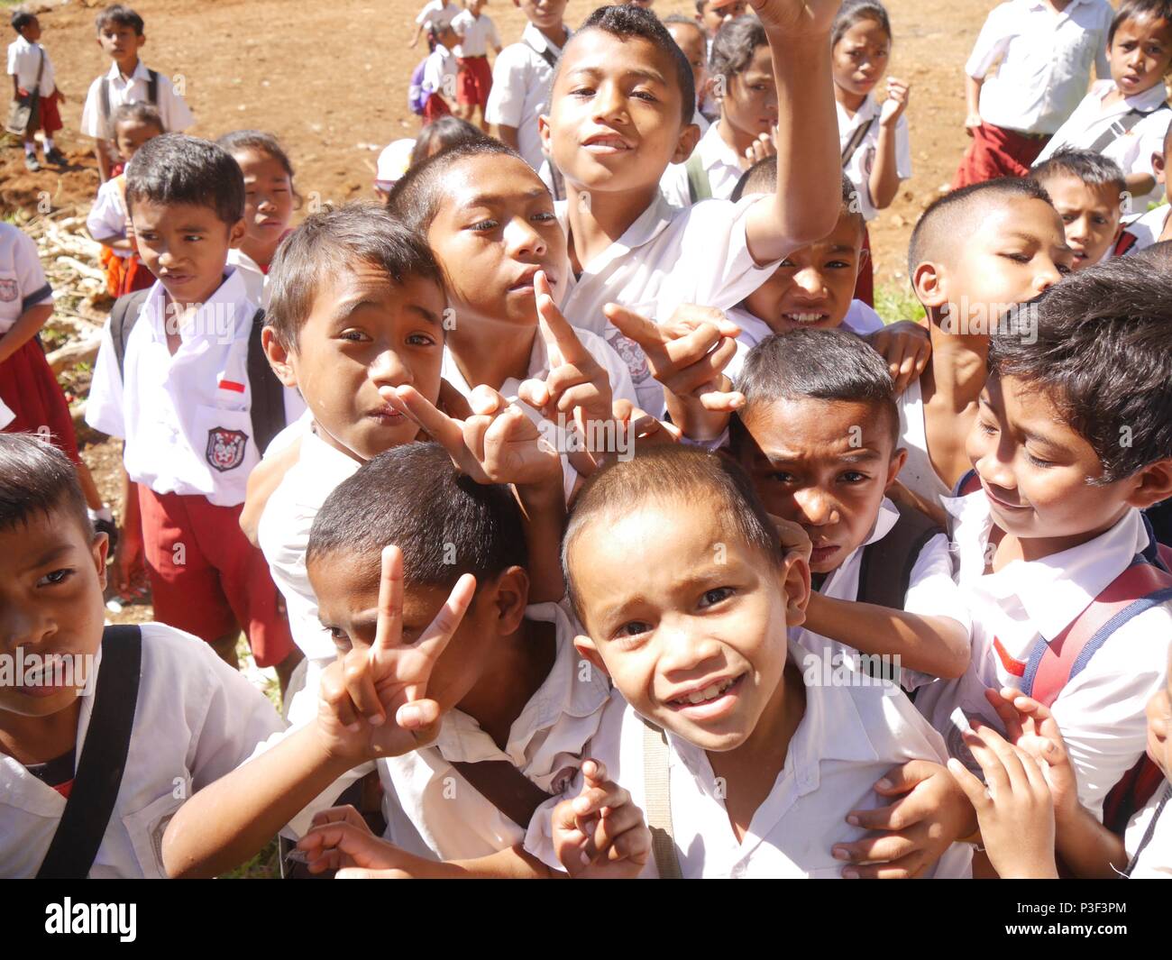 Close up della folla di entusiasti giovane indonesiano a scuola i bambini in uniforme, ragazzi e ragazze, spintoni per posizione, ridendo e sventolare sull isola di Flores Foto Stock