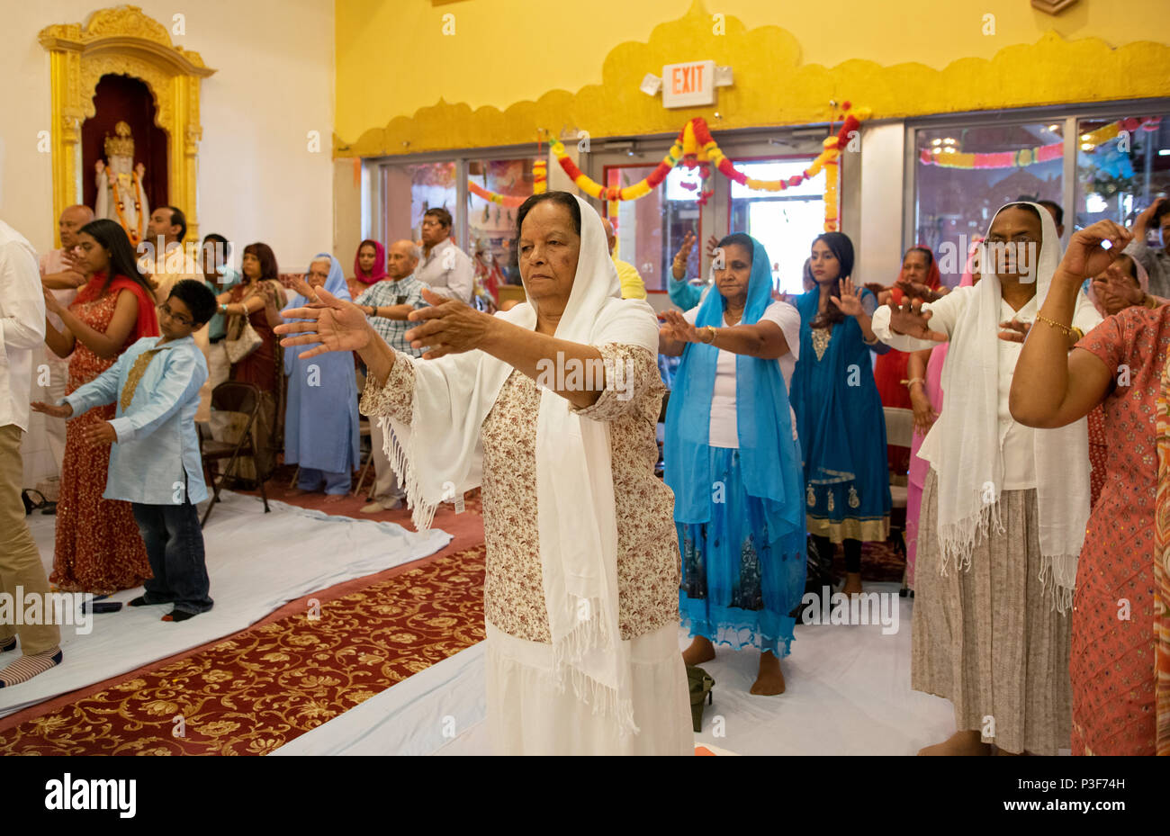 Donne e uomini di pregare con outreached bracci in corrispondenza di Shri Lakshmi Narayan Mandir tempio in Richmond Hill, Queens, a New York. Foto Stock