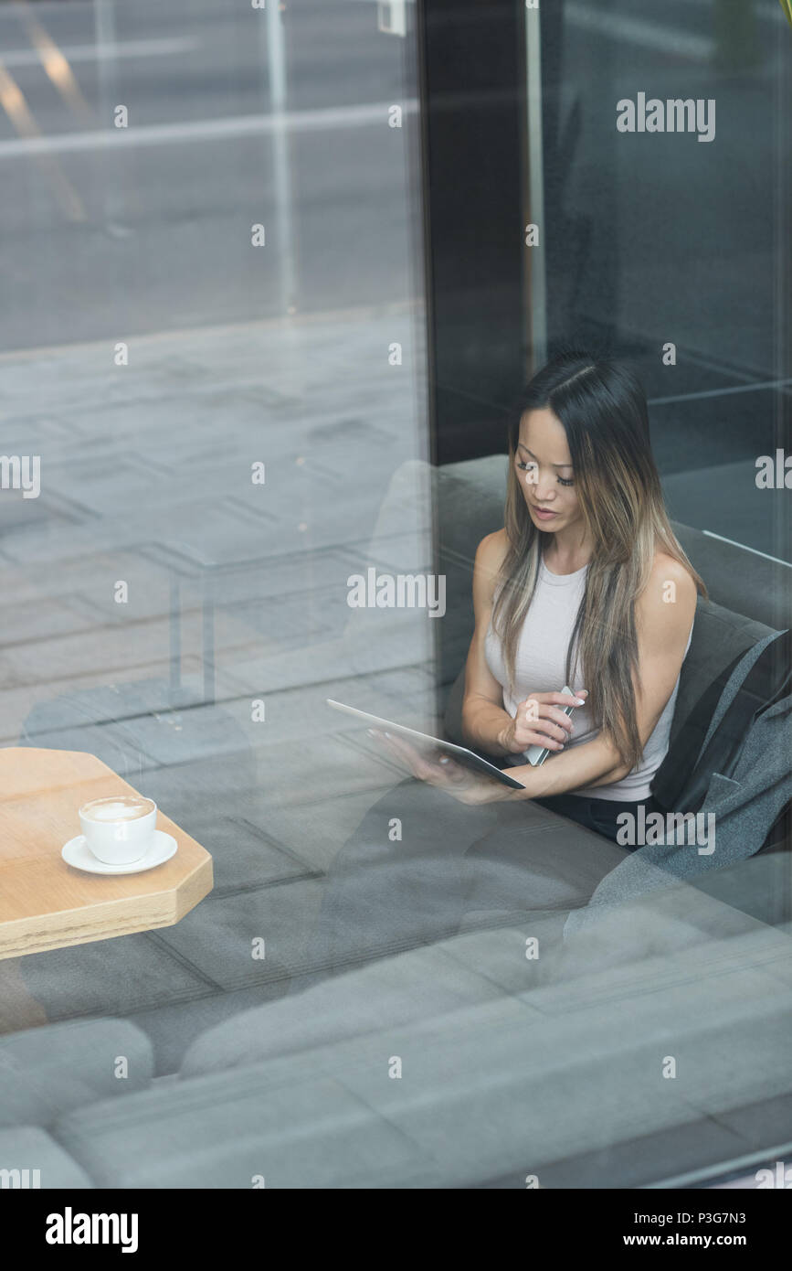 Asian imprenditrice seduto da solo utilizzando il suo tablet Foto Stock