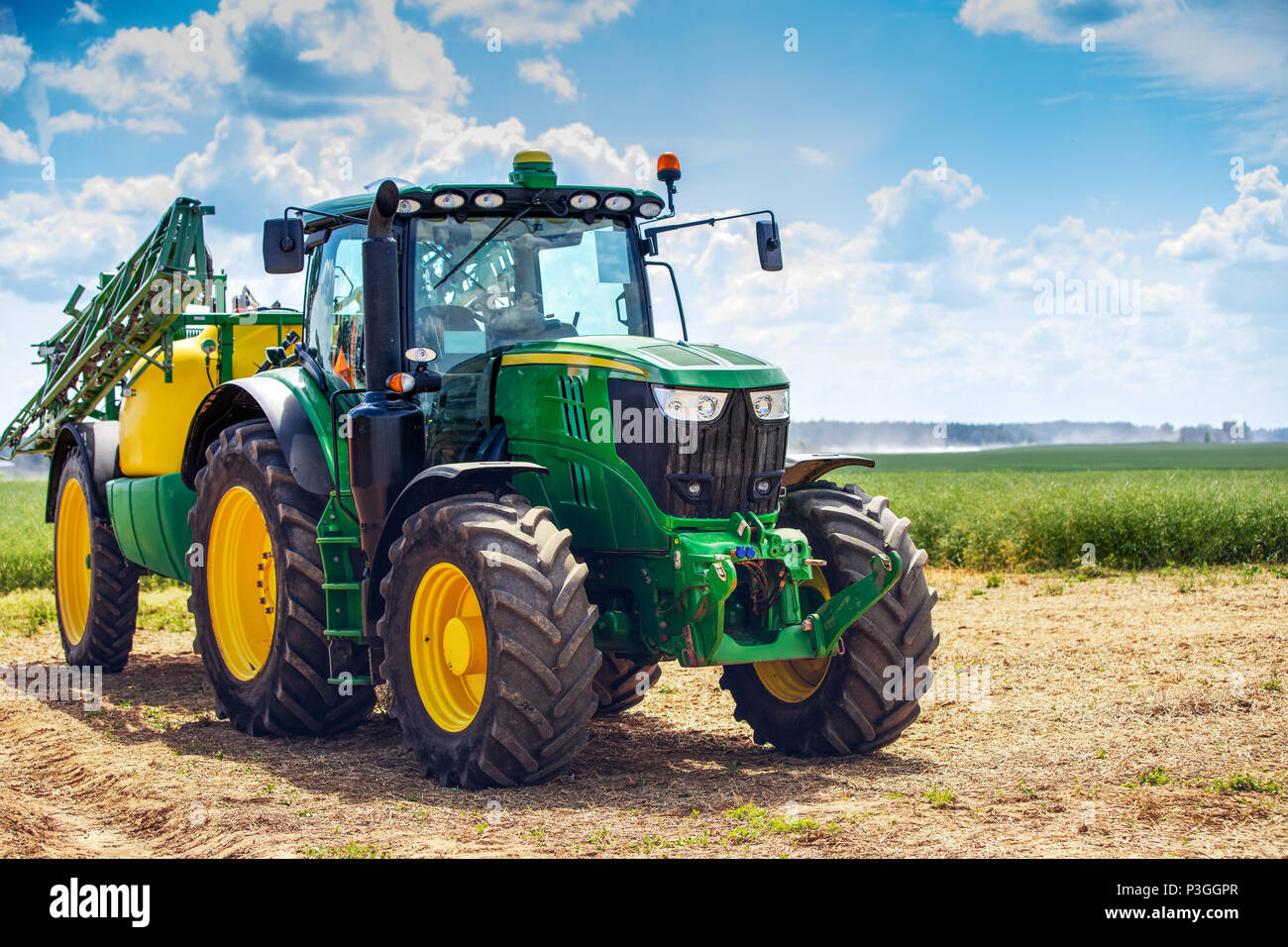 Il trattore con il rimorchio irroratrice accanto al campo di cereali Foto Stock