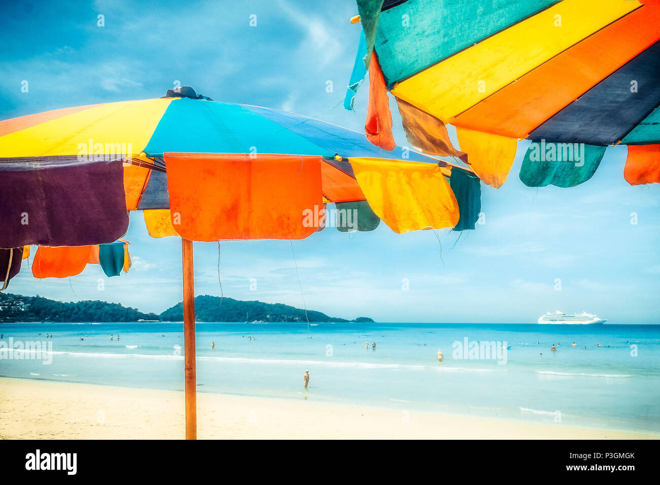 Due ombrelloni colorati in spiaggia su una soleggiata giornata estiva. Estate con sfondo colorato ombrelloni da spiaggia Foto Stock