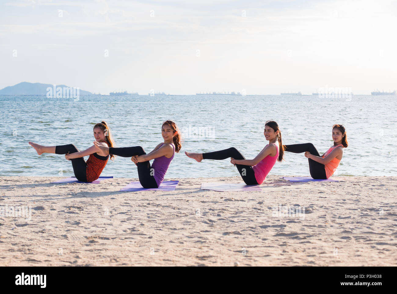 Yoga classe a mare spiaggia in sera ,Gruppo di persone facendo metà barca con vongole emozione relax in spiaggia,Meditazione pongono,Wellness e sano equilibrio vita Foto Stock