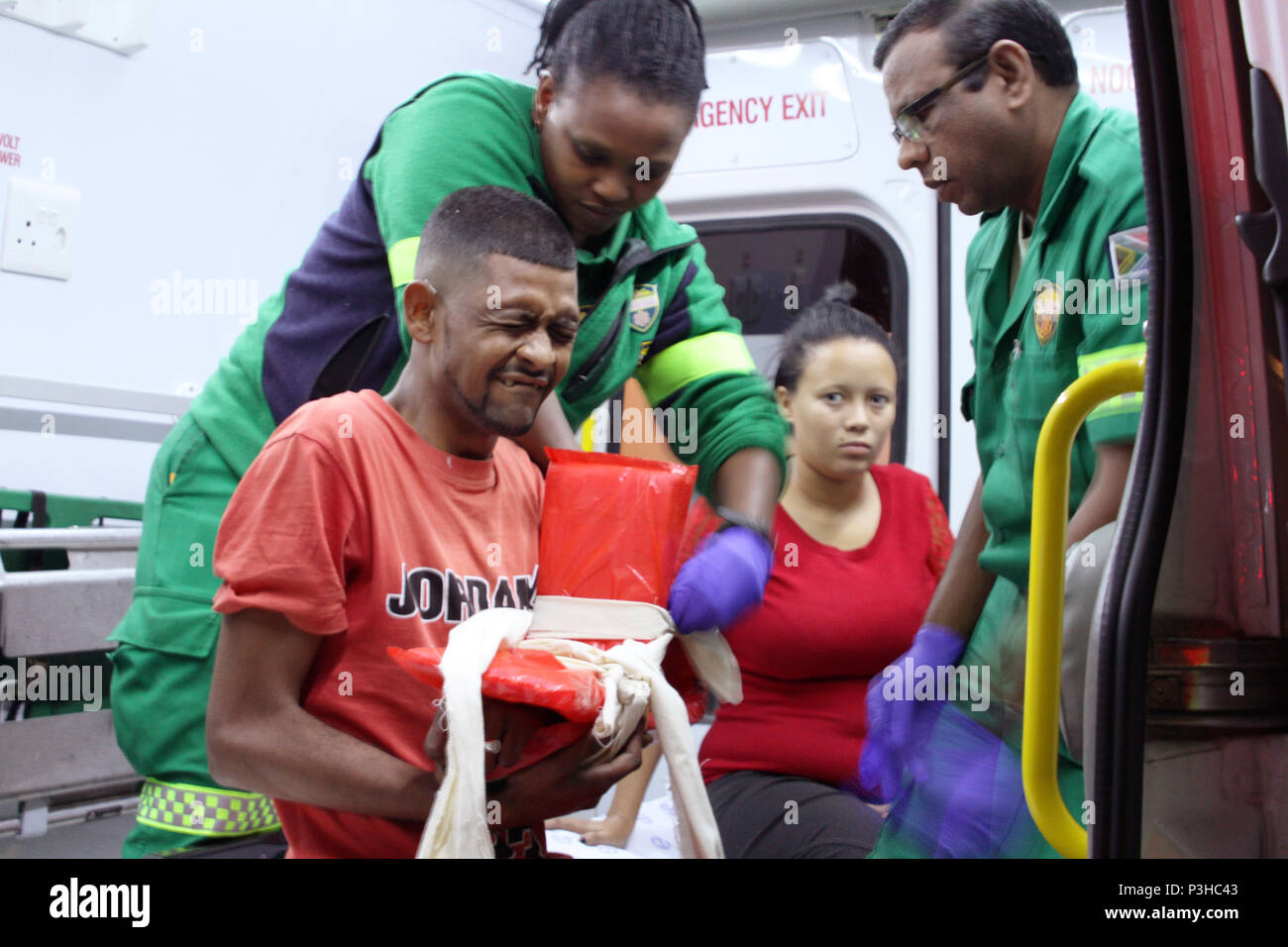 15 maggio 2018, Sud Africa, Cape Town: paramedici Tabisa Saliwa (L) e di Rajendra Laljith (R) trattare la vittima di un incidente. A causa di un alto tasso di criminalità e la guerra fra bande, ambulanze in Sud Africa sono consentite solo per viaggiare di notte in alcune zone - dove la violenza appartiene alla vita di ogni giorno - con la protezione della polizia. Foto: Kristin Palitza/dpa Foto Stock