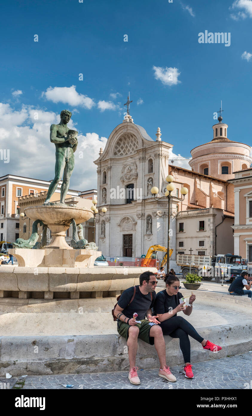 Piazza Duomo, Statua a fontana e la chiesa di Santa Maria del Suffragio, sotto le riparazioni dopo il terremoto del 2009, 2018, vista l'Aquila, Abruzzo, Italia Foto Stock