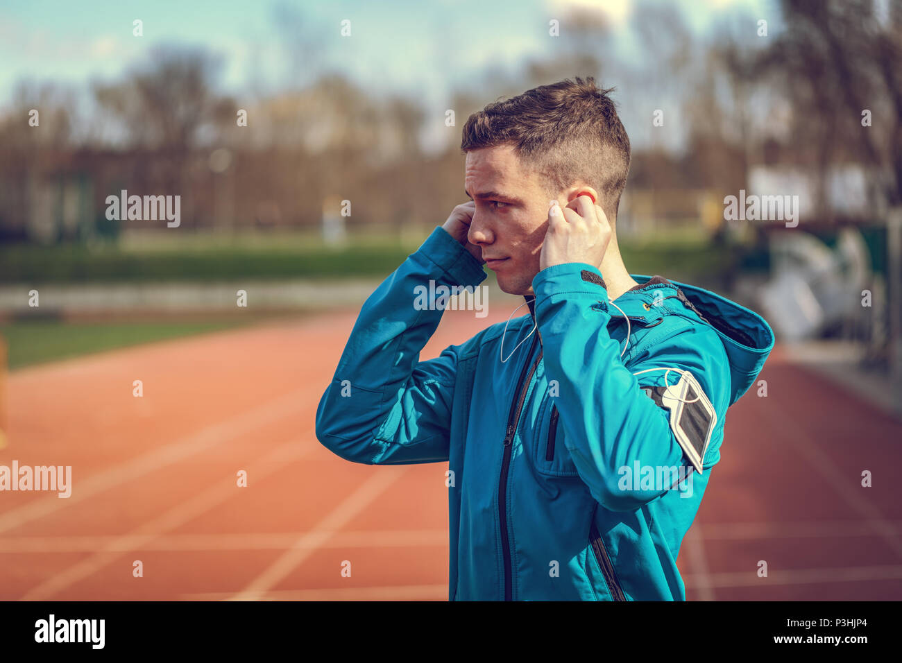 Un maschio di runner con le cuffie sulle orecchie prendendo una pausa in luogo pubblico durante il corso di formazione al di fuori. Copia dello spazio. Foto Stock