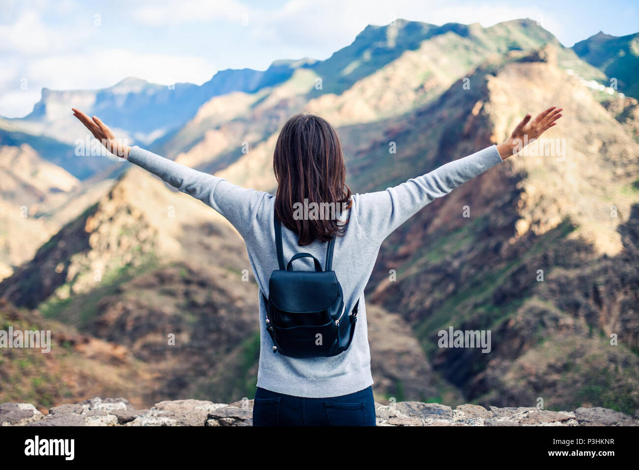 Felice traveler donna con le mani fino godere scenico mountain range paesaggio su Gran Canaria Island dal Mirador del Molino. Concetto di viaggio Foto Stock