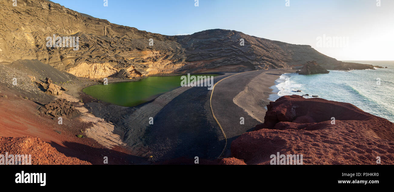 Ampio panorama di una spiaggia nera, il cratere vulcanico con lago verde (El Lago Verde, Charco de los Clicos) in El Golfo. Lanzarote. Isole Canarie. Spagna Foto Stock