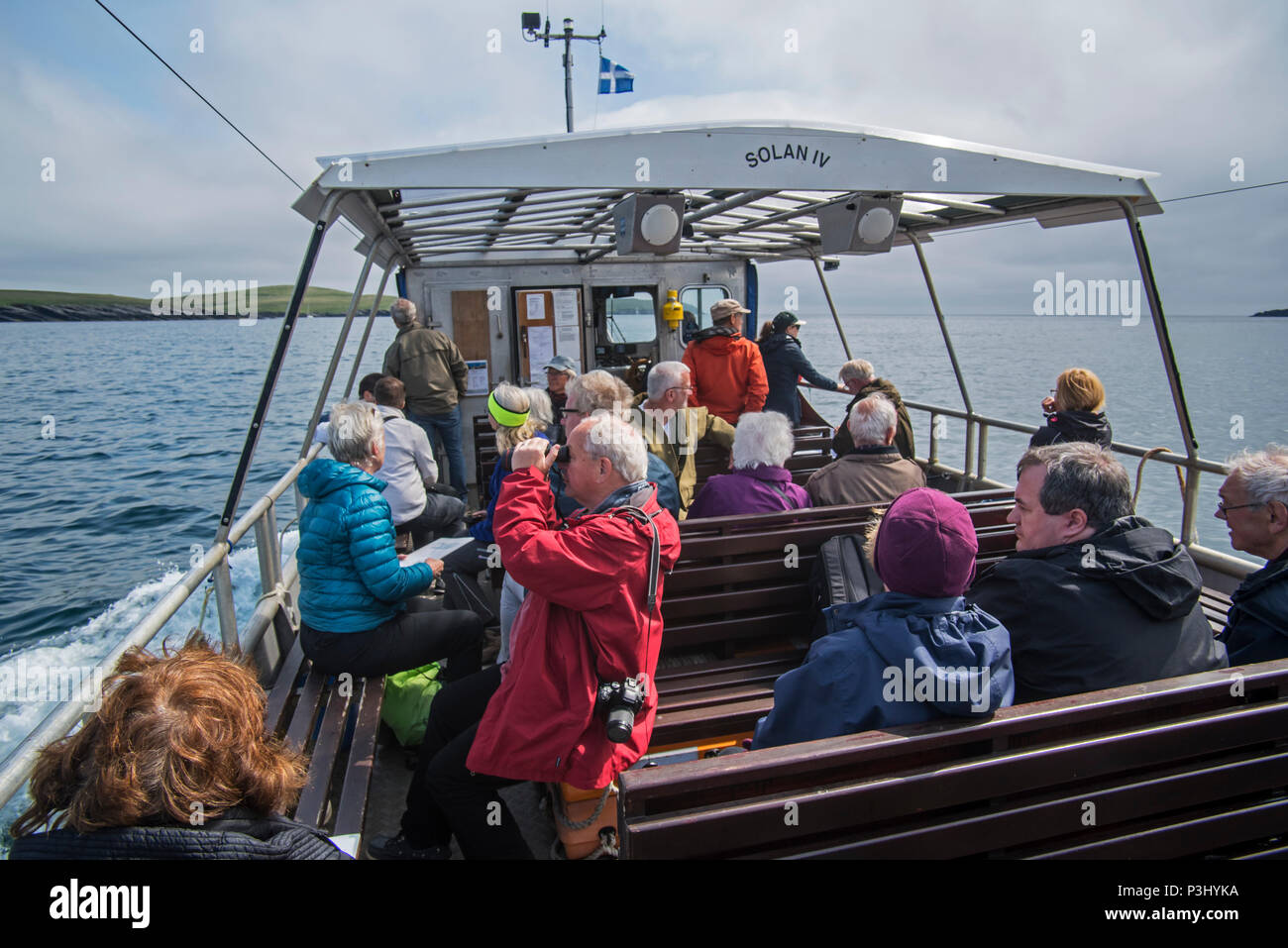 Anziani i turisti a bordo del passeggero aperto ferry boat Solan IV da Leebitton di Mousa la visione di uccelli marini, isole Shetland, Scotland, Regno Unito Foto Stock