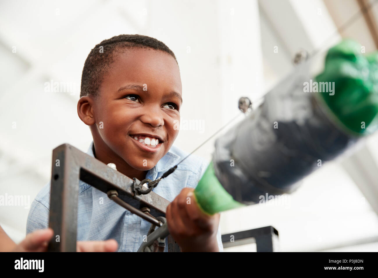 Giovane black boy con pressione aria razzo al science centre Foto Stock