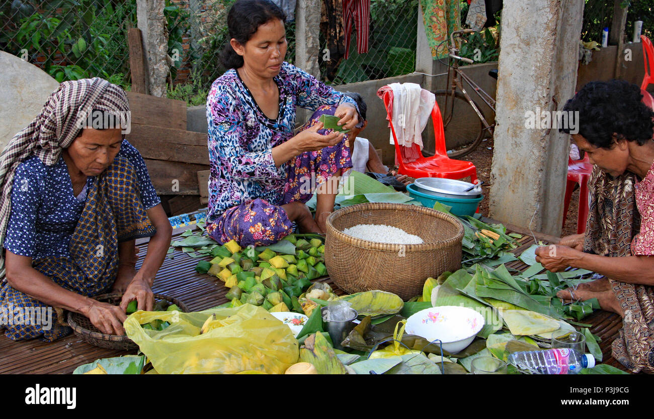 Il giorno prima di un cambogiano di matrimonio la famiglia prepara il banchetto di nozze. I dolci di incarto in pacchi di foglie di banano. Foto Stock