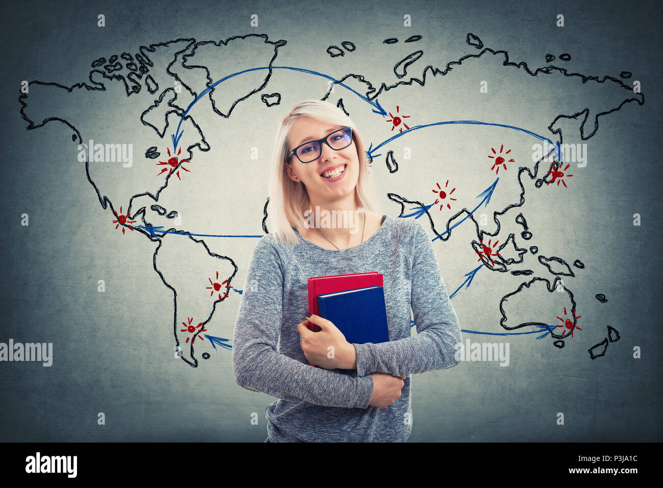 Giovane donna con gli occhiali e tenere due libri sulla mappa del mondo sullo sfondo. L'istruzione globale del concetto. Allegro studente ragazza a pianificare il suo prossimo punto 0 Foto Stock
