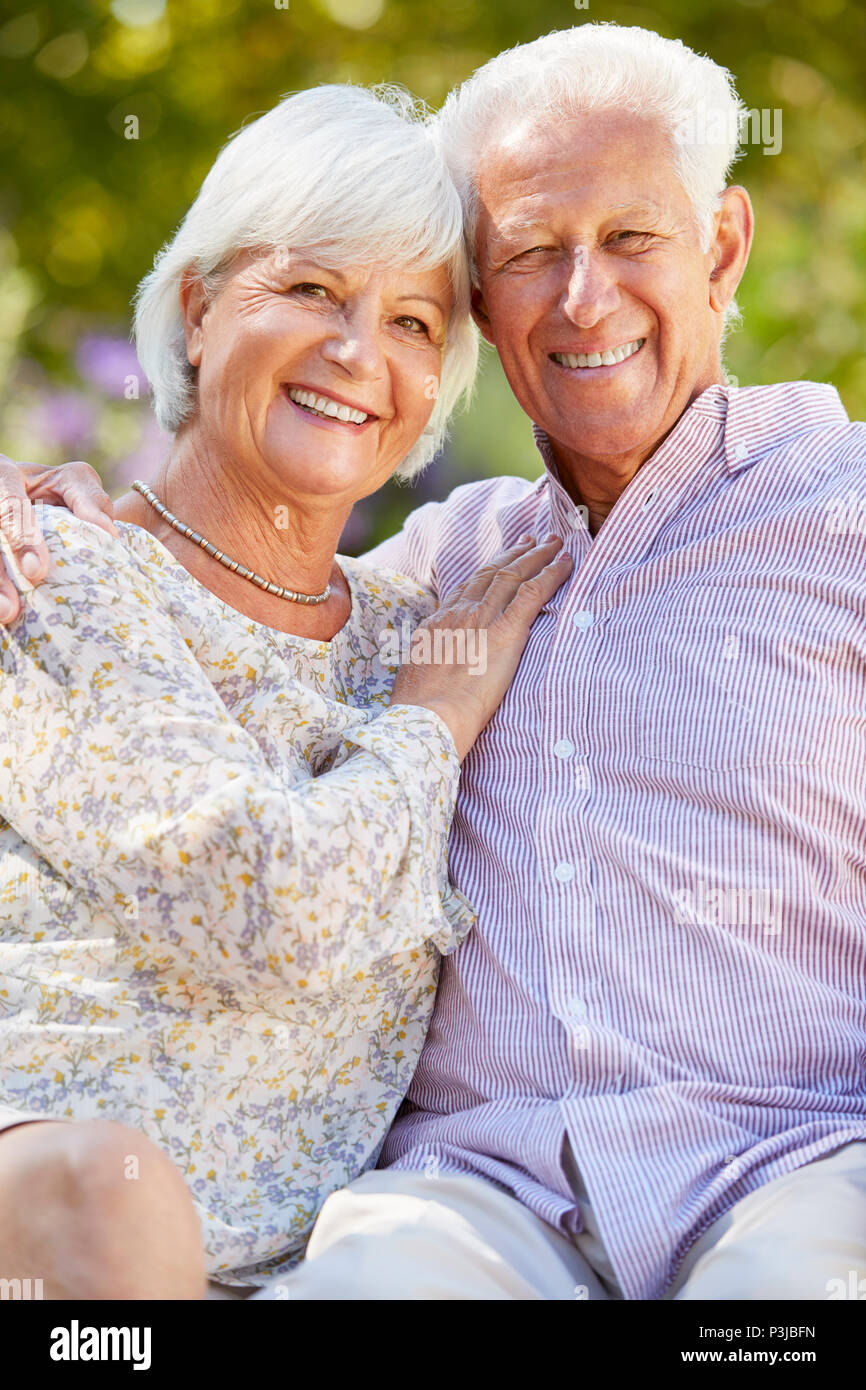 Felice coppia senior seduti in giardino abbracciando Foto Stock
