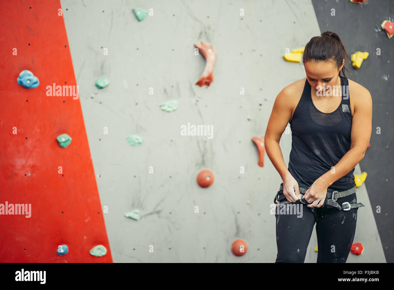 Trainer digitando elettrico della donna sulla parete di arrampicata in palestra Foto Stock