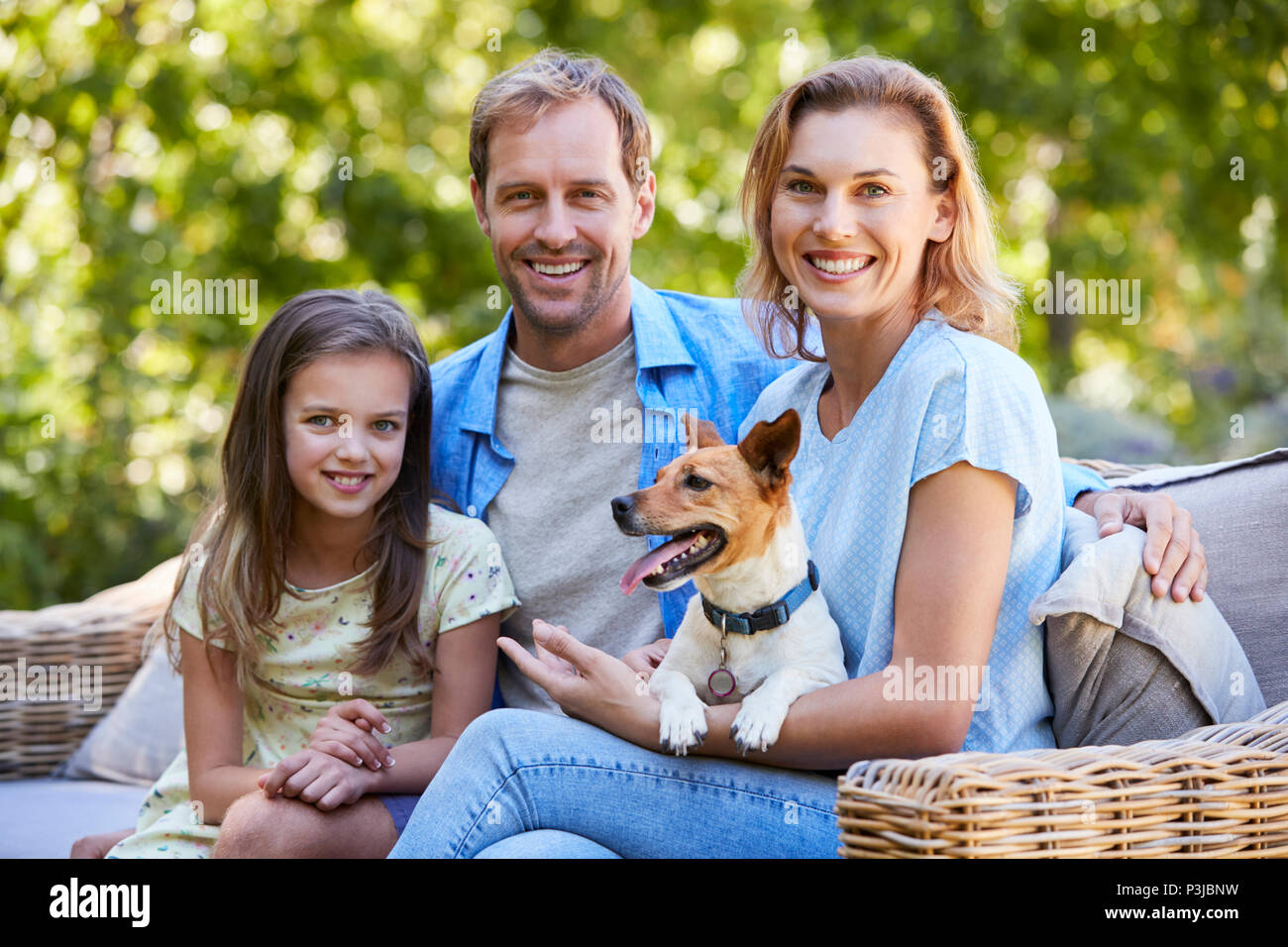 I genitori e la figlia seduta con il loro cane in giardino Foto Stock