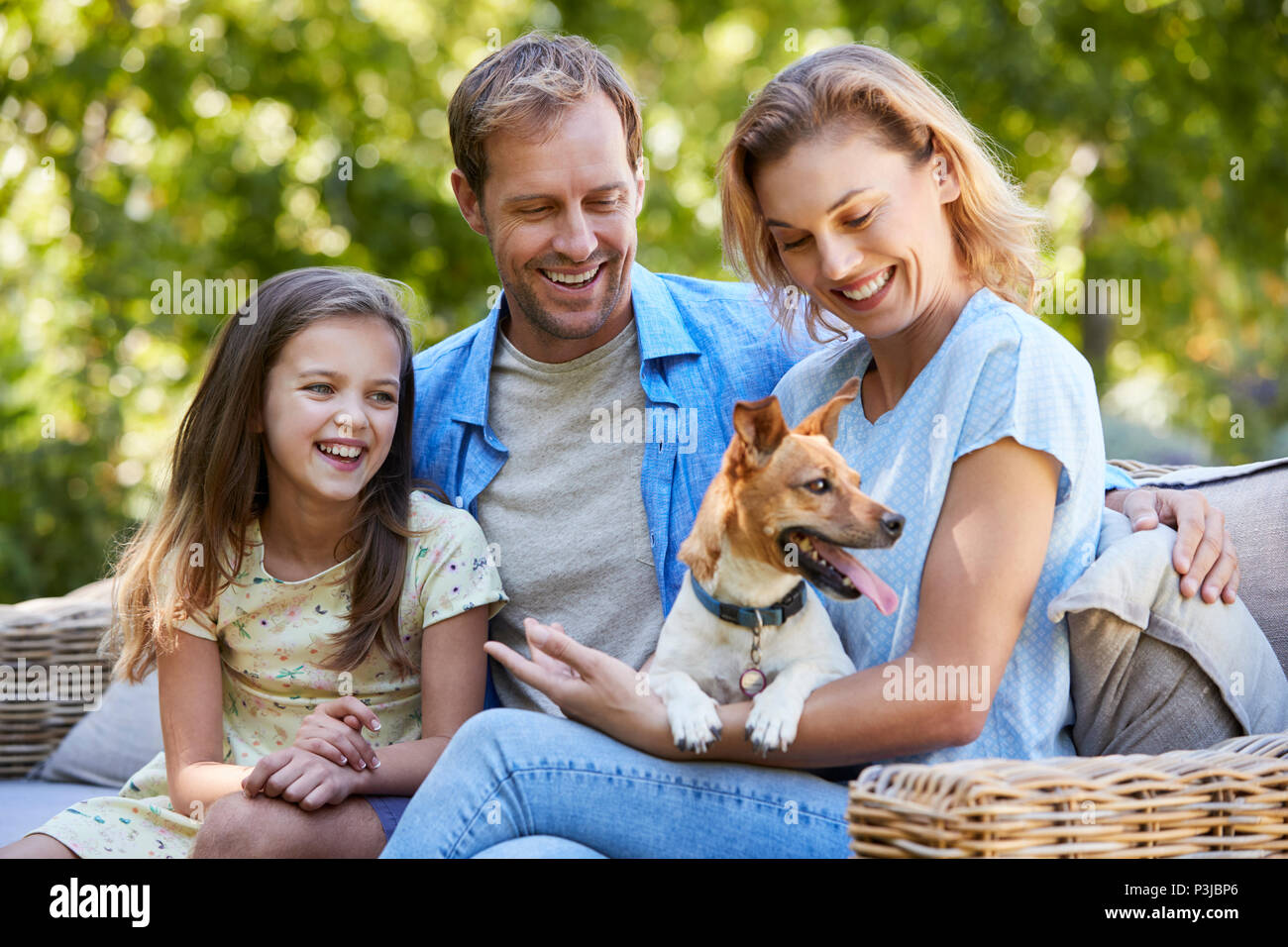 I genitori e la figlia seduta con il loro cane in giardino Foto Stock
