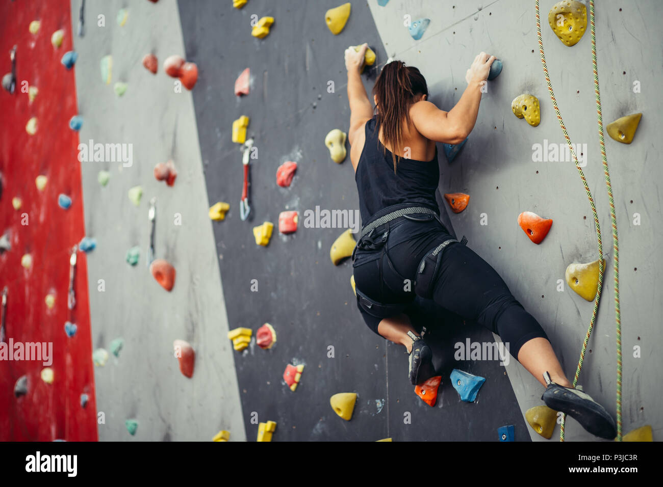 Sportivo da donna giovane la formazione in un colorato palestra di arrampicata. Foto Stock