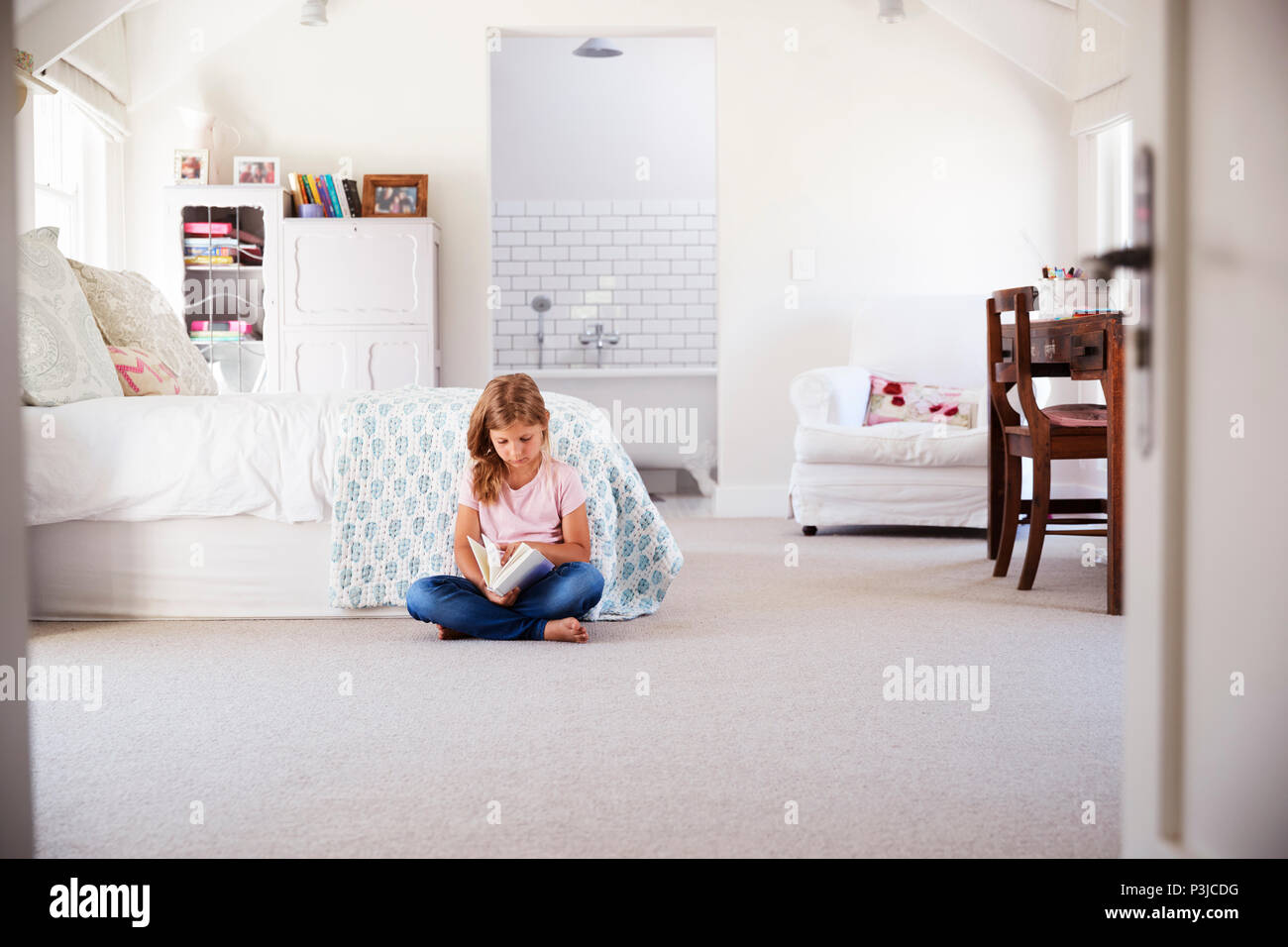 Ragazza giovane la lettura di un libro da sola nella sua camera da letto Foto Stock