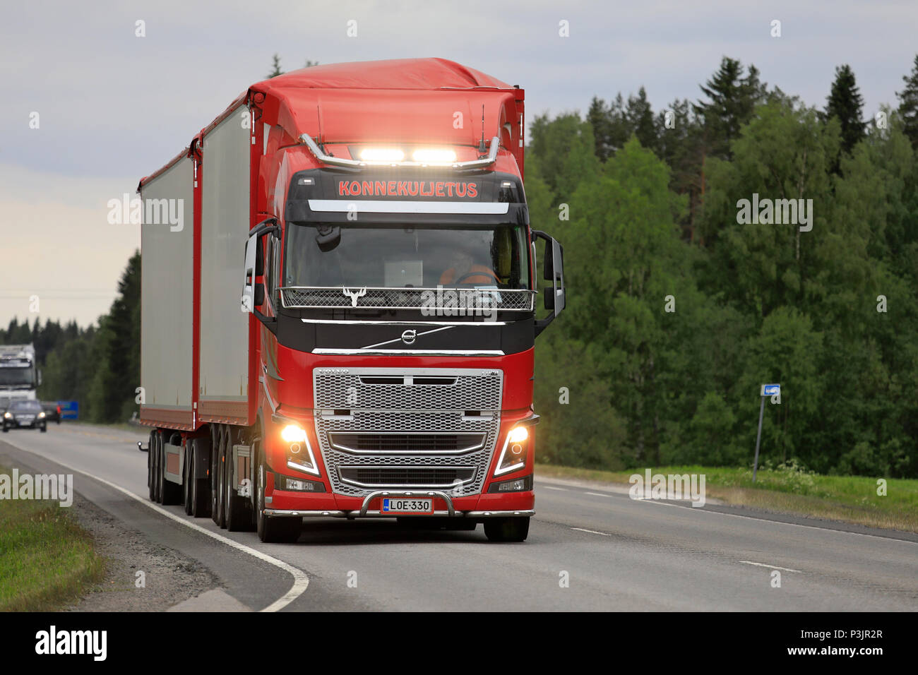 Red Volvo FH carrello e rimorchio pieno di Konnekuljetus Oy autotrasporti su autostrada, con luci ausiliarie per la foto. Uurainen, Finlandia - 15 giugno 2018 Foto Stock