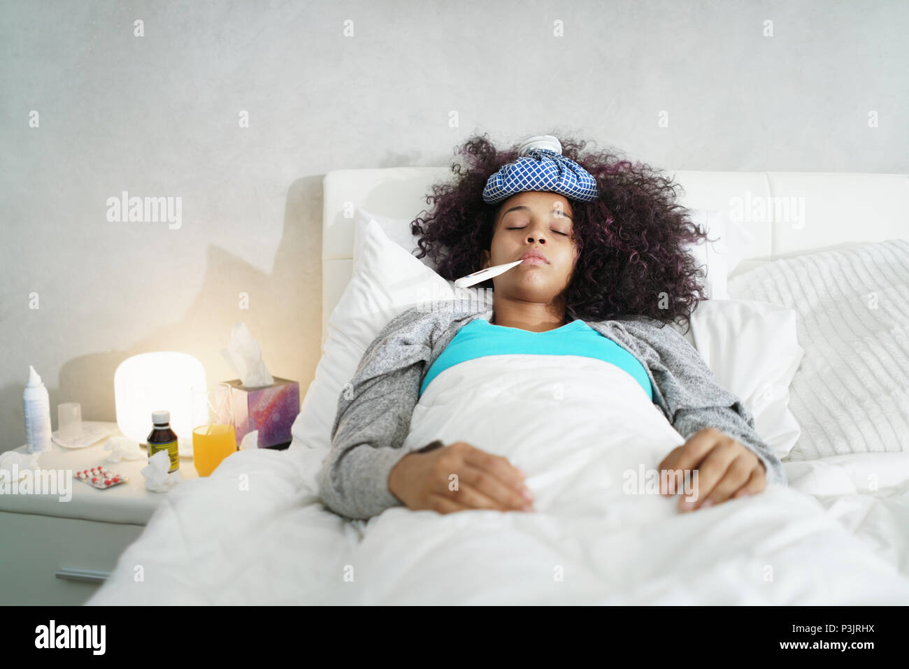 Donna con la febbre con il termometro e il riposo a letto Foto stock - Alamy