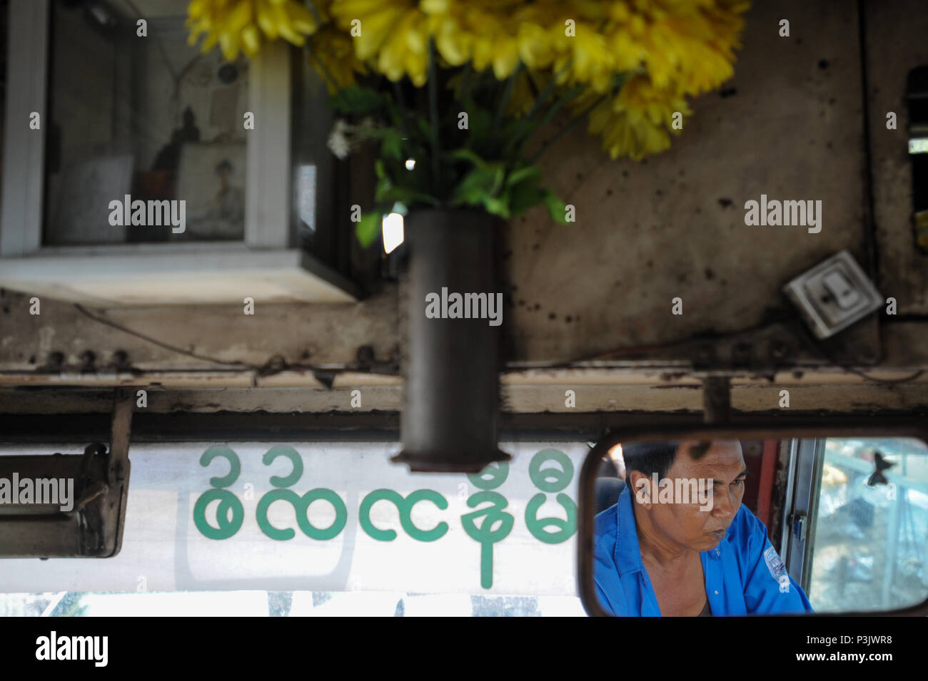 Yangon, Myanmar, la faccia di un autista di autobus è riflesso nel retrovisore Foto Stock