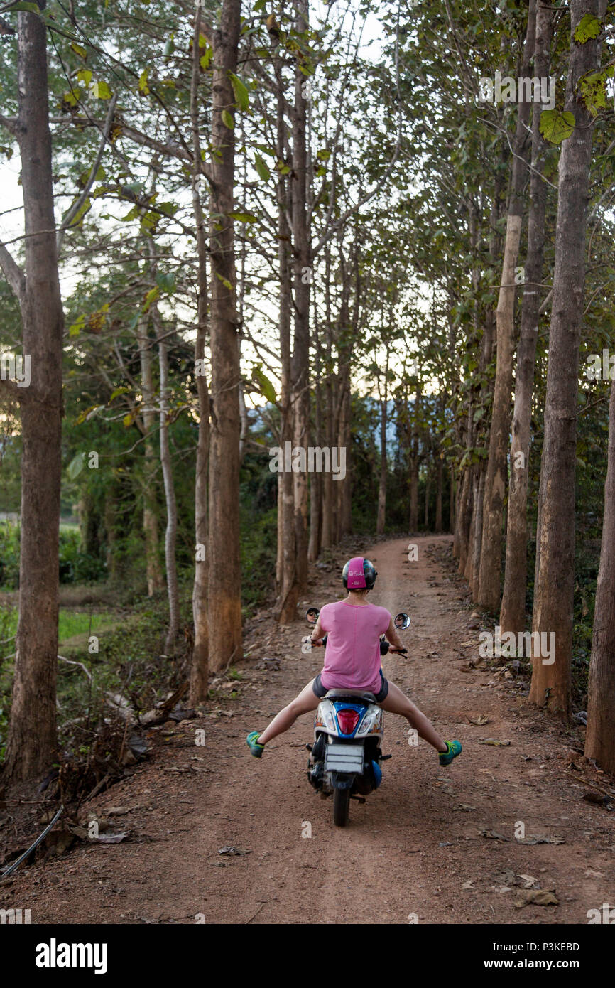 Equitazione donna scooter su strada forestale, Pai, Mae Hong presto, Thailandia Foto Stock
