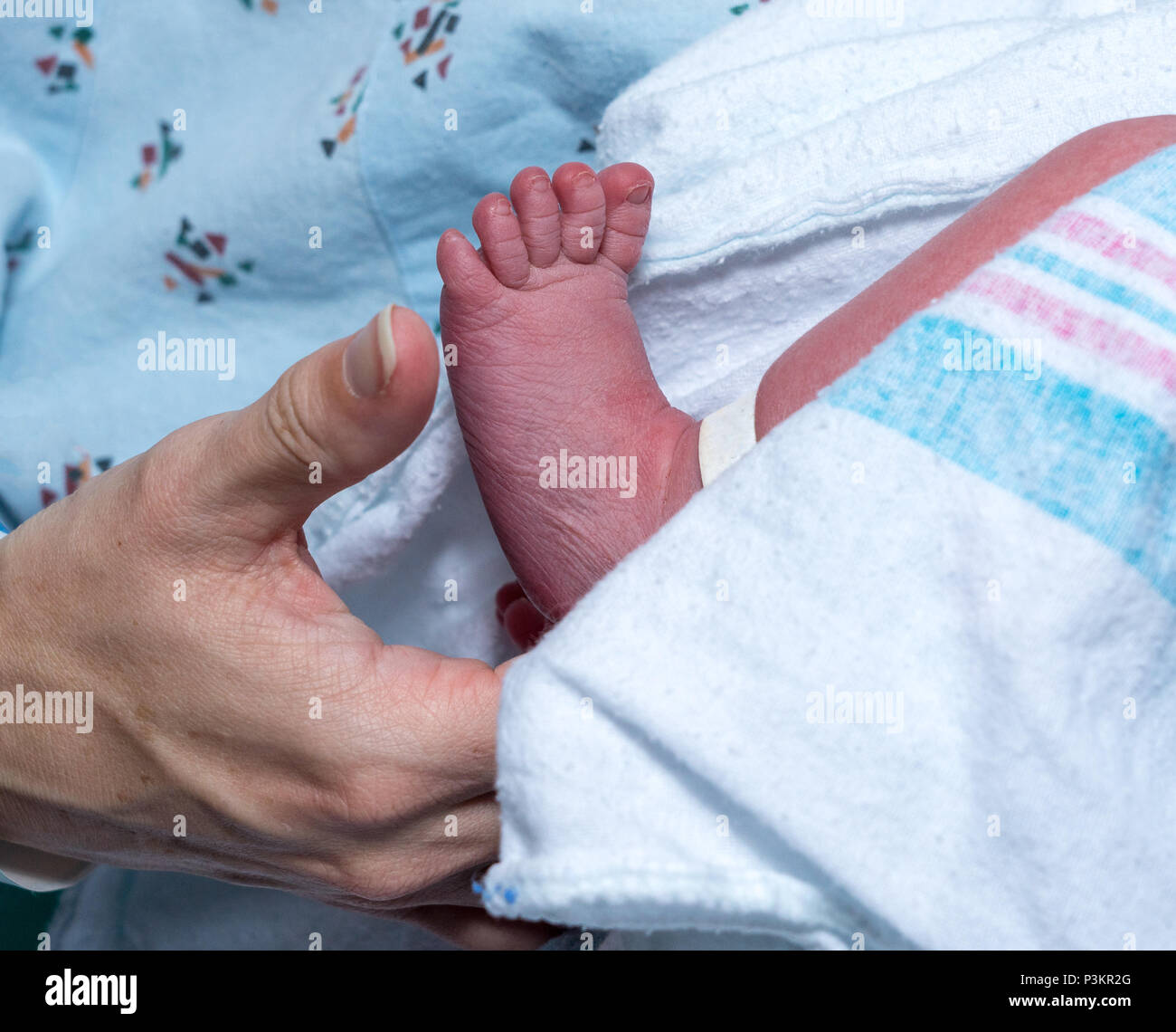 Madre tenendo delicatamente il piede del figlio neonato Foto Stock