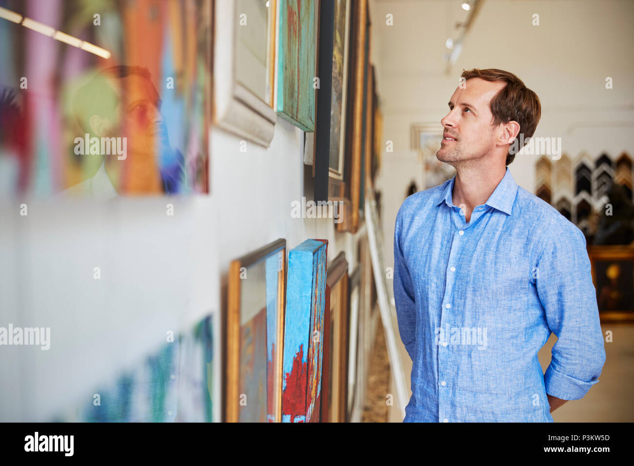 Uomo che guarda dipinti nella Galleria d'arte Foto Stock