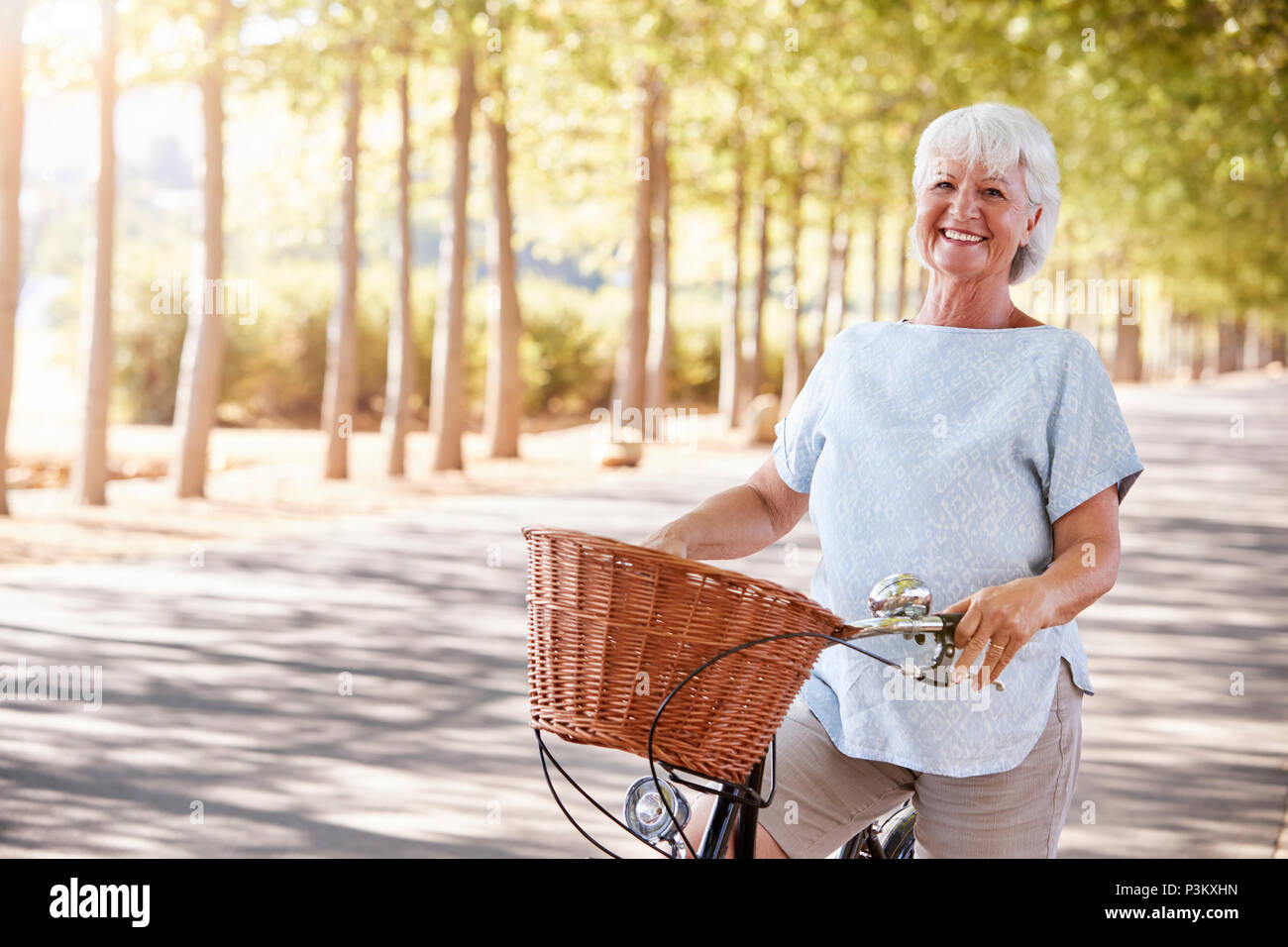 Ritratto di sorridente donna Senior di ciclismo su strada di campagna Foto Stock