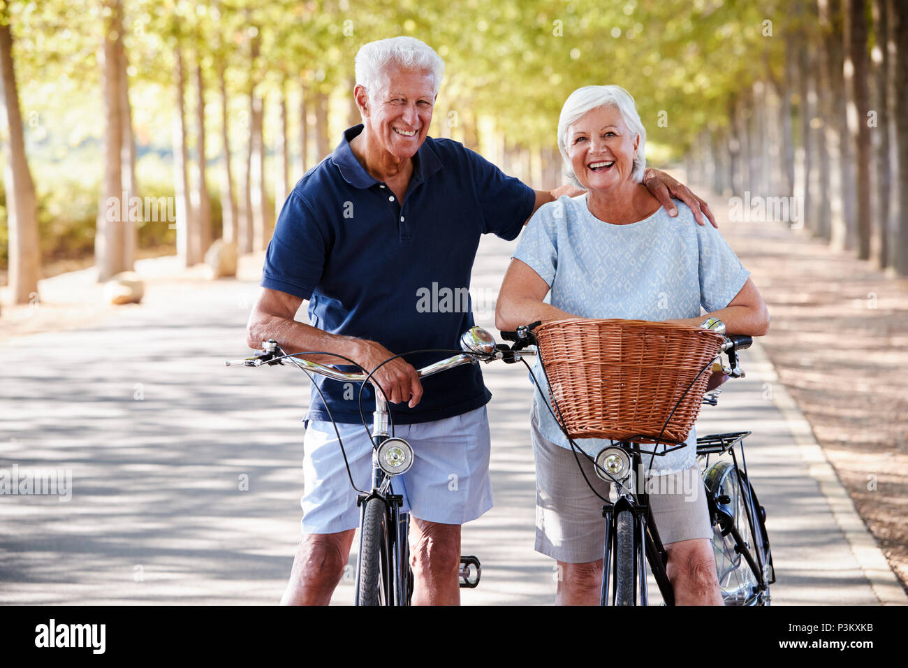 Ritratto di sorridente coppia Senior ciclismo su strada di campagna Foto Stock