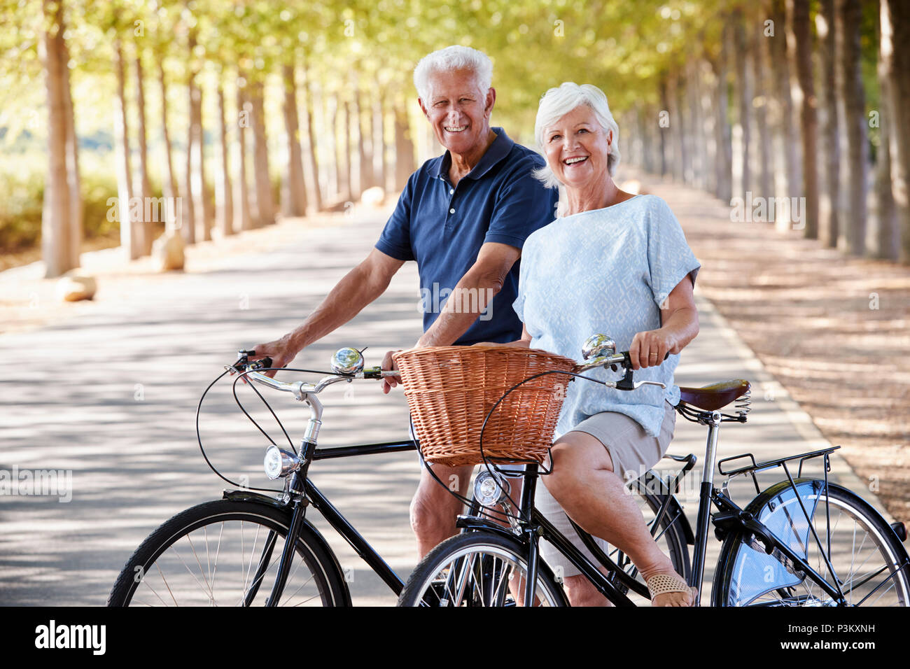Ritratto di sorridente coppia Senior ciclismo su strada di campagna Foto Stock