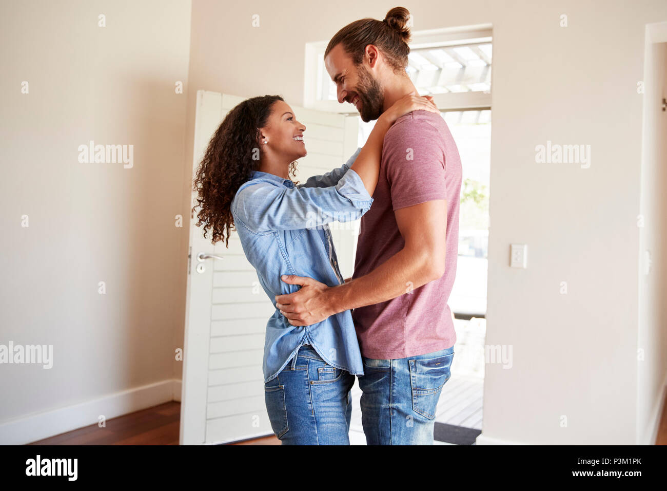 Eccitato giovane costeggiata dalla porta anteriore aperta nel salotto della nuova casa Foto Stock