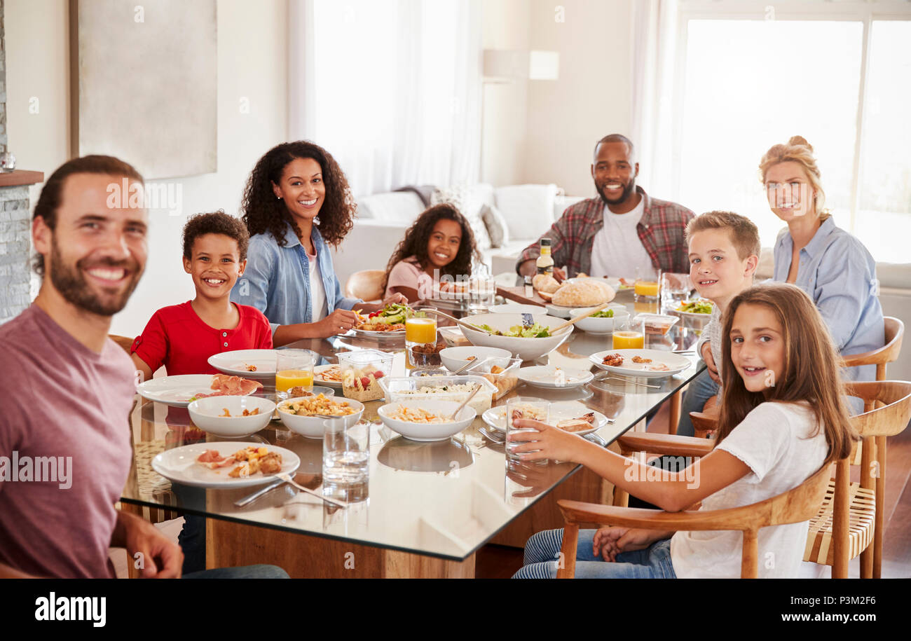 Ritratto di due famiglie in quanto essi godono di pasto a casa insieme Foto Stock