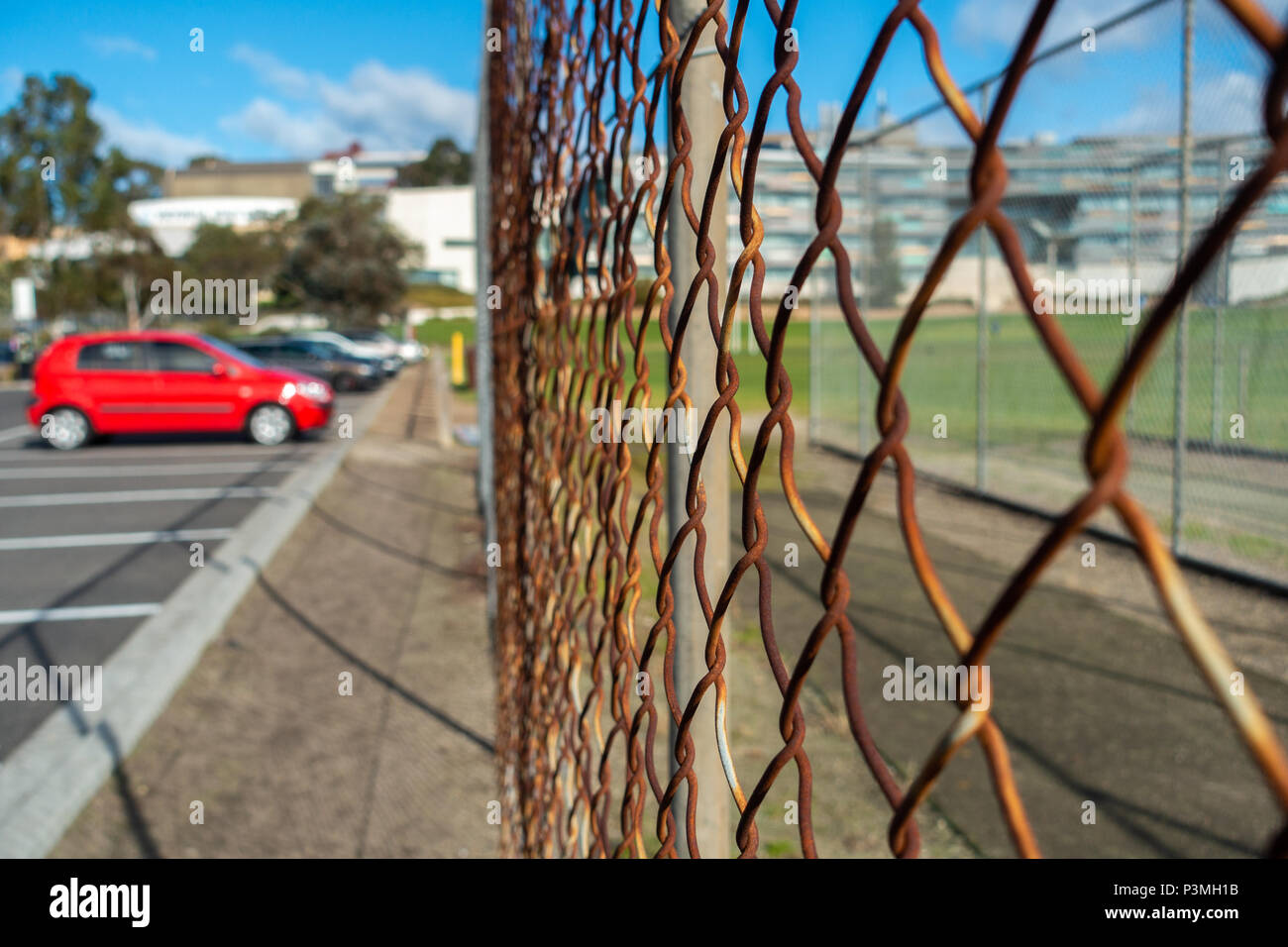 Close up di rustico wire mesh vicino parcheggio auto esterno. Foto Stock