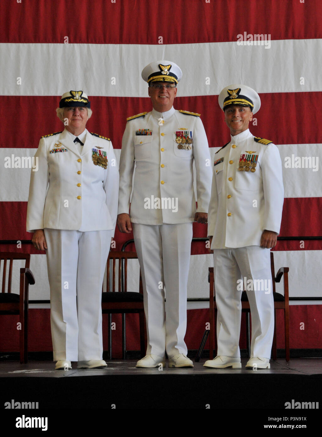 Il cap. Keith cavalcavia (destra) alleviato Capt. Patricia McFetridge (sinistra) come il comandante della stazione di aria Borinquen durante un cambio del comando cerimonia presieduta da Adm posteriore. Scott Buschman (centro), Coast Guard settimo distretto, comandante della base aeromobili hangar Luglio 8, 2016 in Aguadilla, Puerto Rico. Stazione aria Borinquen personale, insieme con il gruppo di quattro MH-65D Dolphin elicotteri, condurre operazioni di ricerca e salvataggio, l'applicazione della legge, Homeland security, marine la tutela ambientale, alieno di interdizione del migrante e counterdrug delle missioni in tutta l'area caraibica orientale di responsa Foto Stock