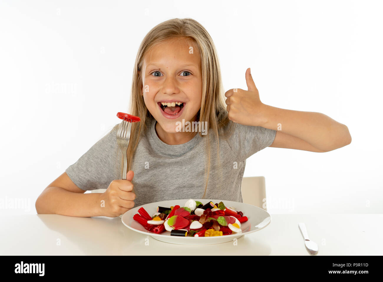 Funny Girl felice con la piastra di candy lollipop lollies felice bambina mangiare grandi zucchero candito lollies kid mangiare dolci. bambino sorpreso con la caramella. iso Foto Stock