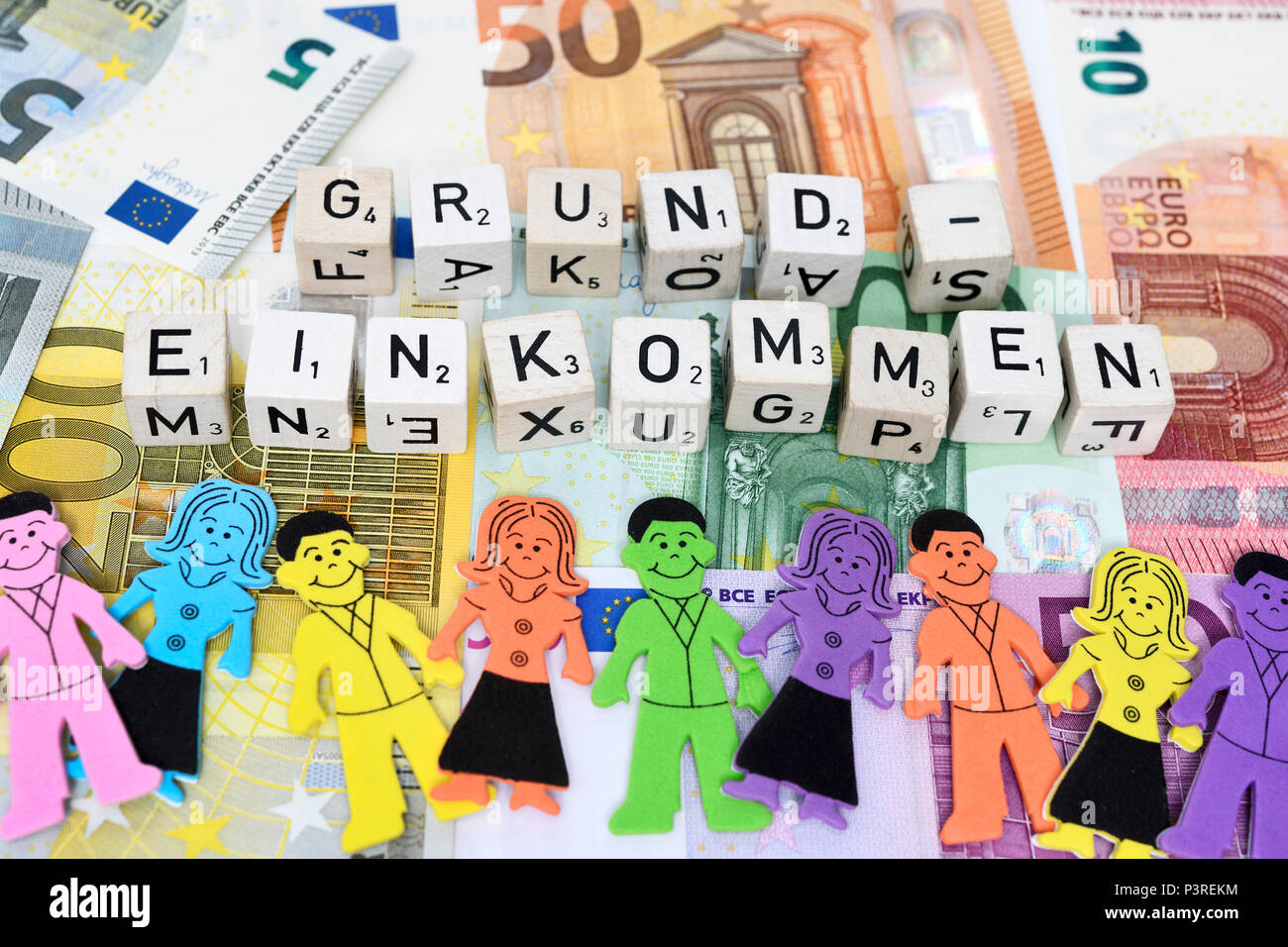 Lettera cube forma la parola reddito base sul denaro, Buchstabenwürfel formen das Wort Grundeinkommen auf Geldscheinen Foto Stock