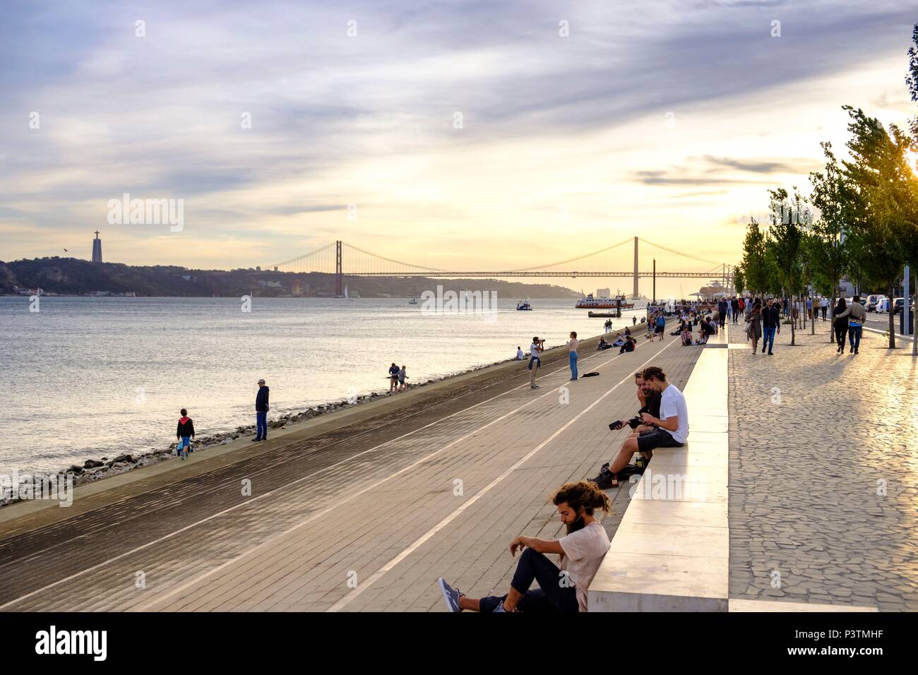 La vita di strada sul Fiume Tagus Lisbona Promenade affacciata sul Ponte 25 de Abril Bridge, Lisbona, Portogallo Foto Stock