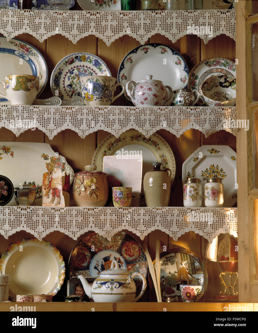 Colose di vintage piatti di porcellana cinese e teiere su scaffali di pino con bordo in pizzo Foto Stock
