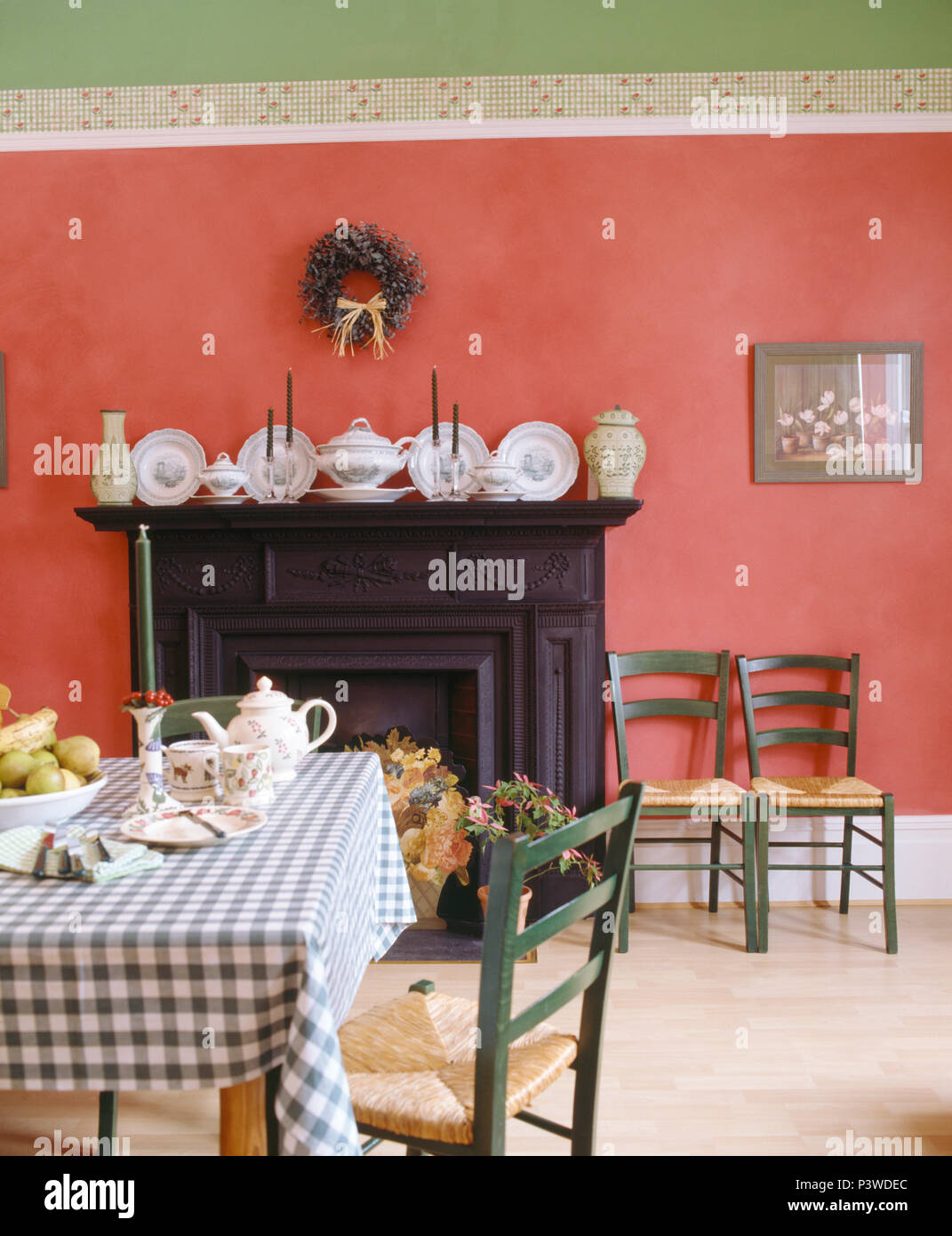 Controllare blu panno sul tavolo in deep pink camera da pranzo con raccolta di Cina in ghisa nera camino Foto Stock