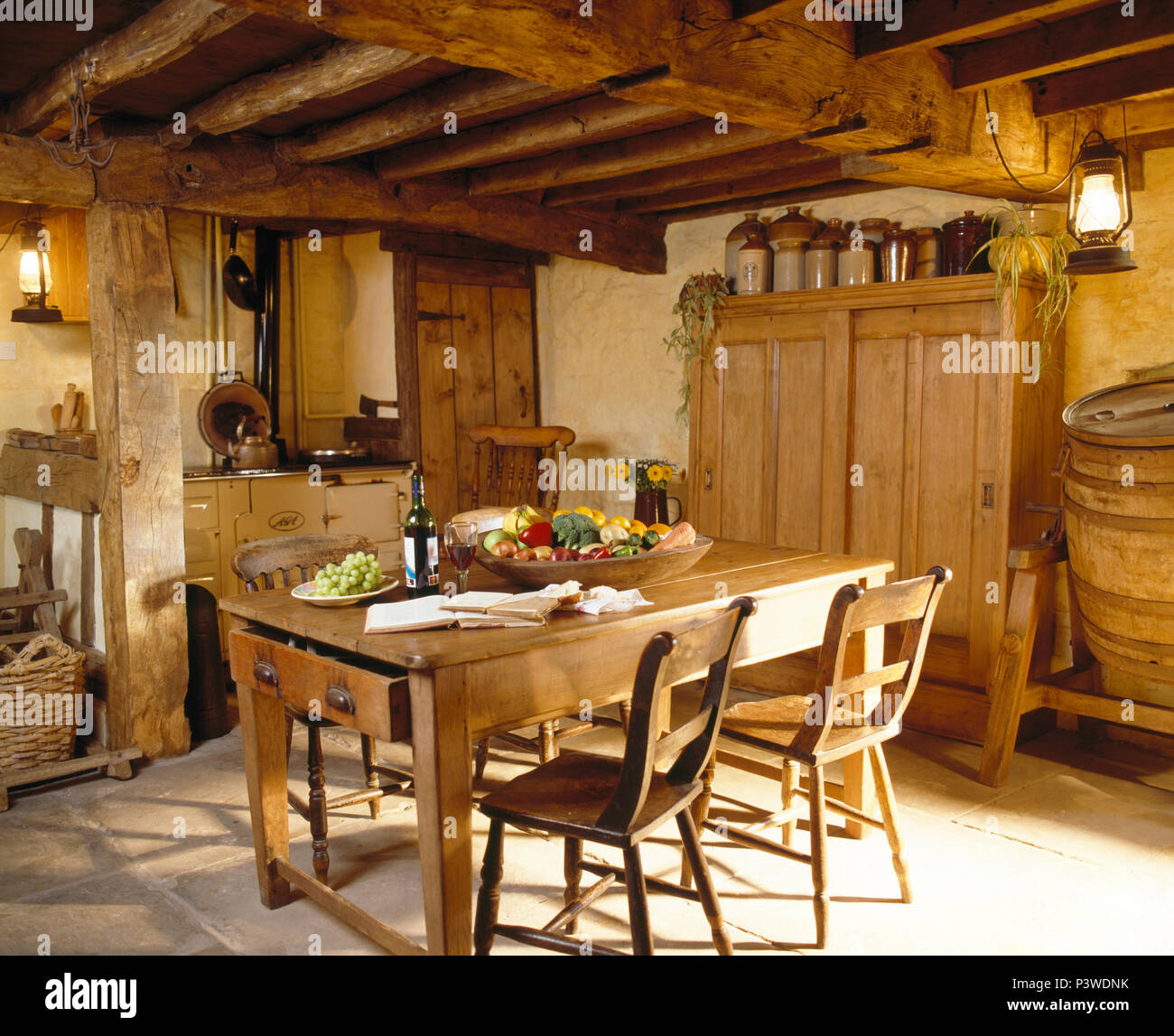 Pine tavolo e sedie in basso soffitto con travi a vista, cucina cottage con crema di AGA e grande pino ripostiglio Foto Stock