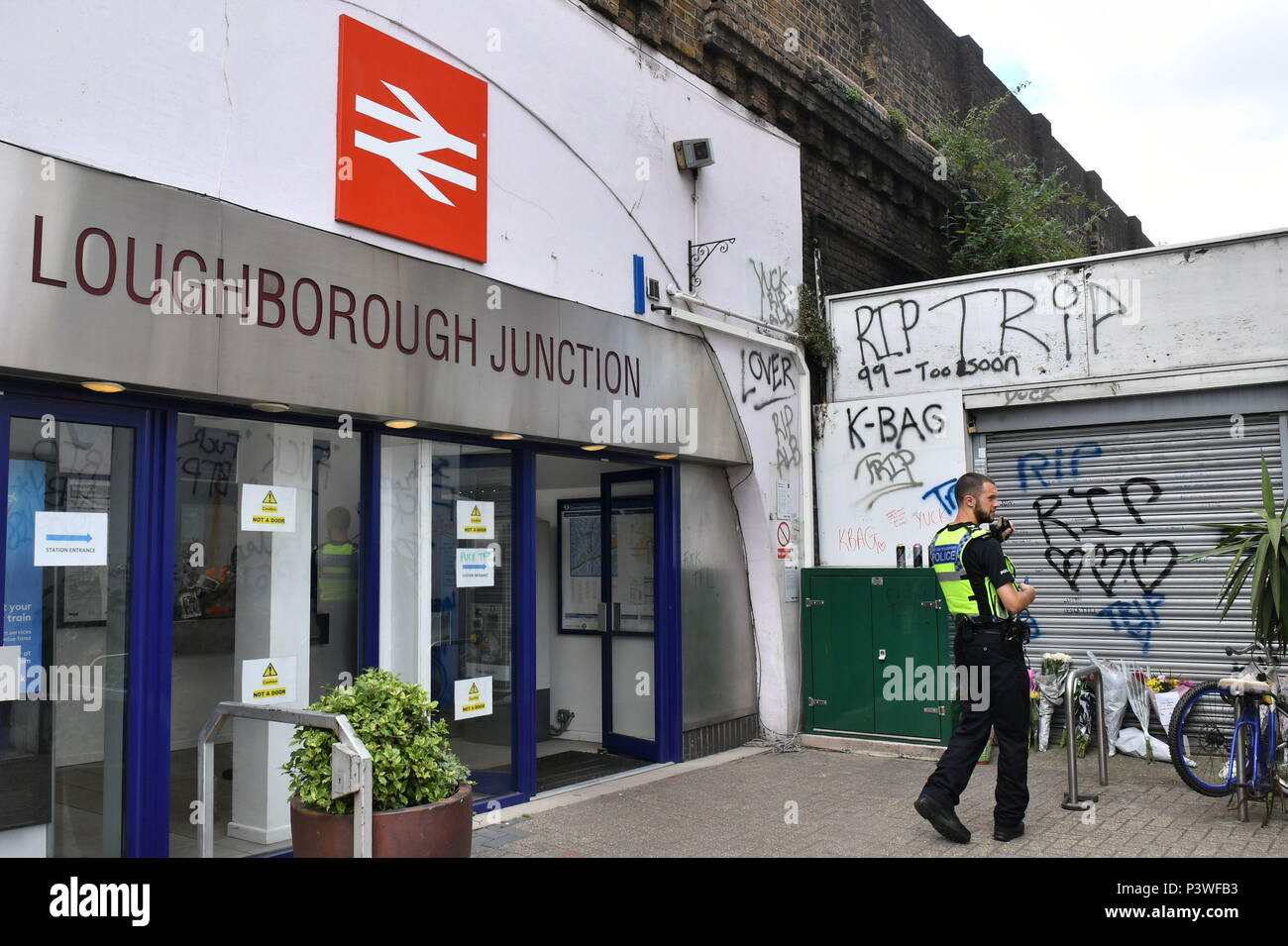 Fiori e tre bombolette spray lay accanto a otturatori che sono state spray-verniciato con 'RIP' e tre cuori, a Loughborough giunzione stazione ferroviaria, vicino a Brixton a Londra Sud, dove i membri del London street art scena hanno pagato un tributo a tre uomini che è morto dopo essere stato colpito da un treno. Foto Stock