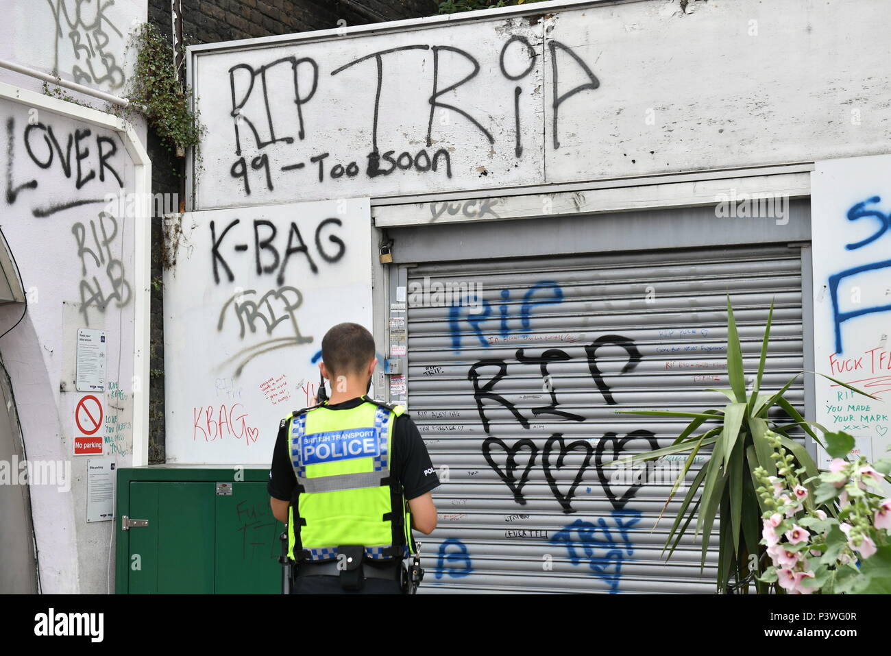 Fiori e tre bombolette spray lay accanto a otturatori che sono state spray-verniciato con 'RIP' e tre cuori, a Loughborough giunzione stazione ferroviaria, vicino a Brixton a Londra Sud, dove i membri del London street art scena hanno pagato un tributo a tre uomini che è morto dopo essere stato colpito da un treno. Foto Stock